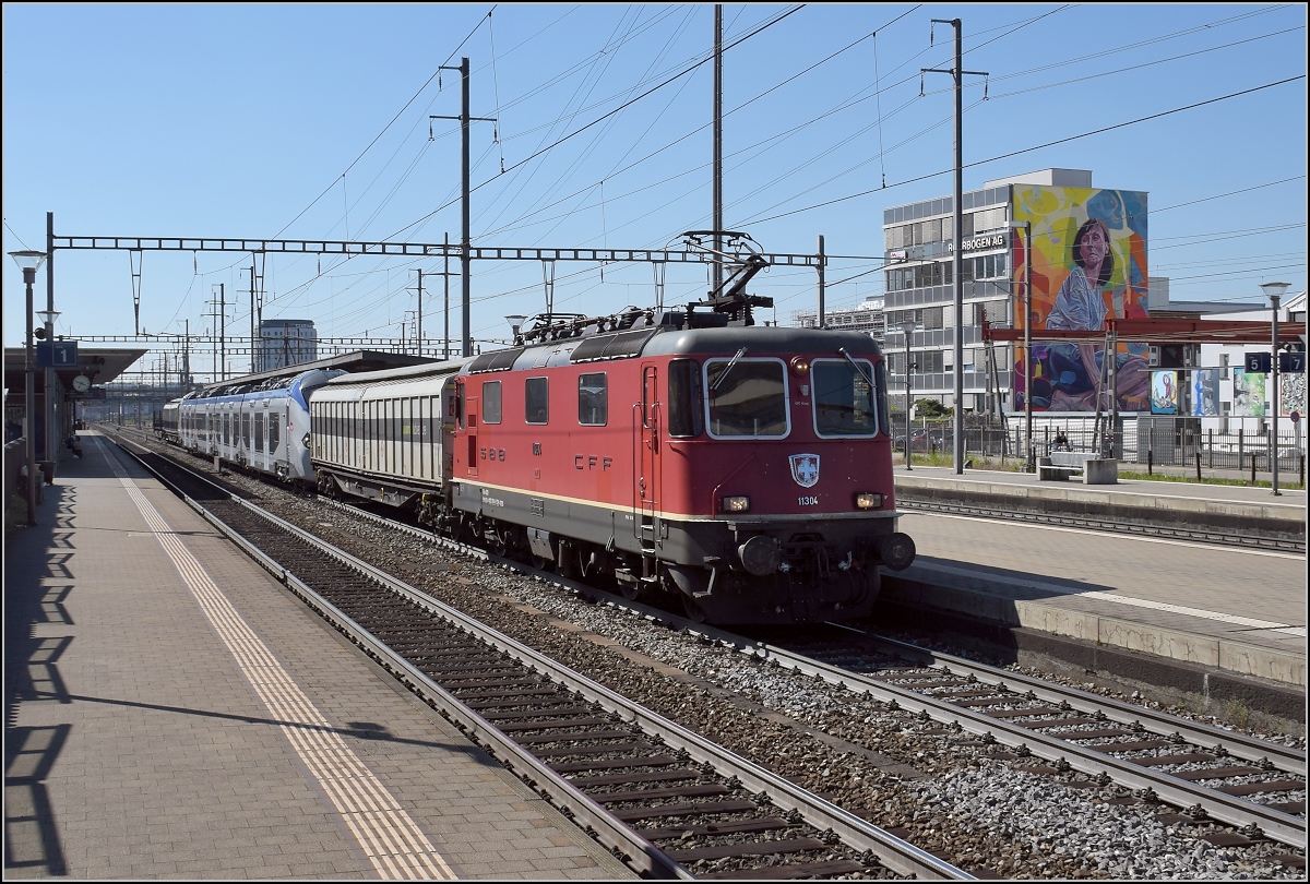 Re 4/4 11304 überstellt eine interessante Fuhre Richtung Olten: Regiolis tricourant Z 31501 M der SNCF. Pratteln, April 2017. 