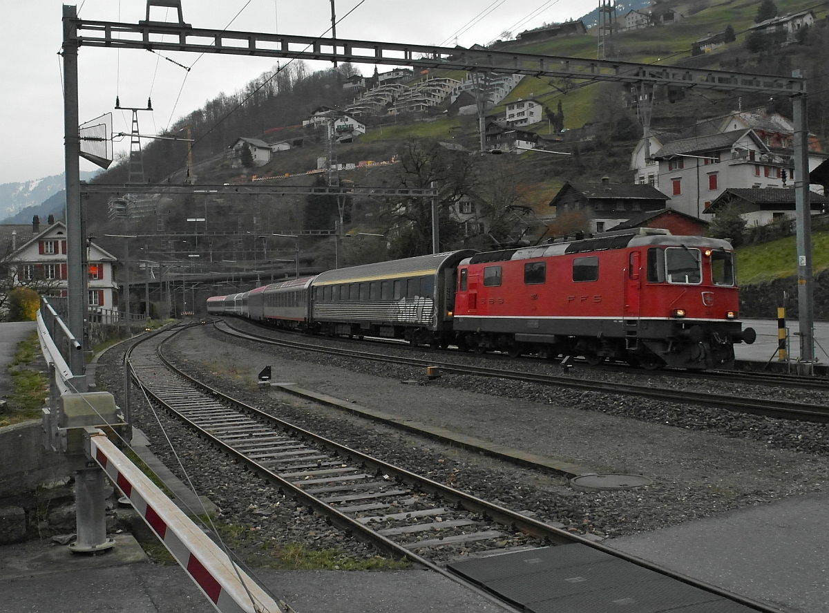 Re 4/4 II 11124 mit einer bunten Zusammenstellung von unterschiedlichen Wagen des EN 464 von Graz nach Zürich fährt am 16.03.2014 durch Mühlehorn.