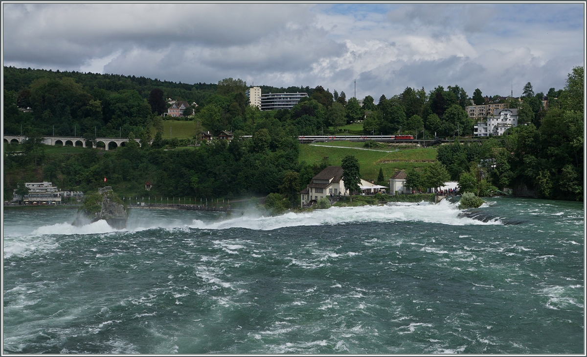Rheinfall - während der Rhein zu Tale stürzt, fährt eine SBB Re 4/4 mit einem IC kurz vor Neuhausen in Richtung Schaffhausen.

18. Juni 2016