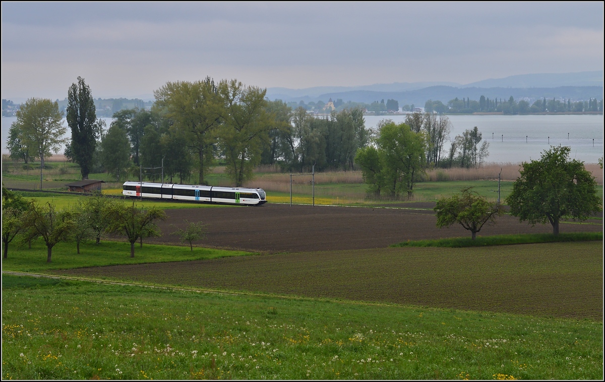 Sauwetter bei Triboltingen. 

S-Bahn Schaffhausen-Herisau mit GTW der Thurbo am Untersee. Im Hintergrund St. Georg, Teil des Unesco Weltkulturerbes auf der Reichenau. Mai 2014.