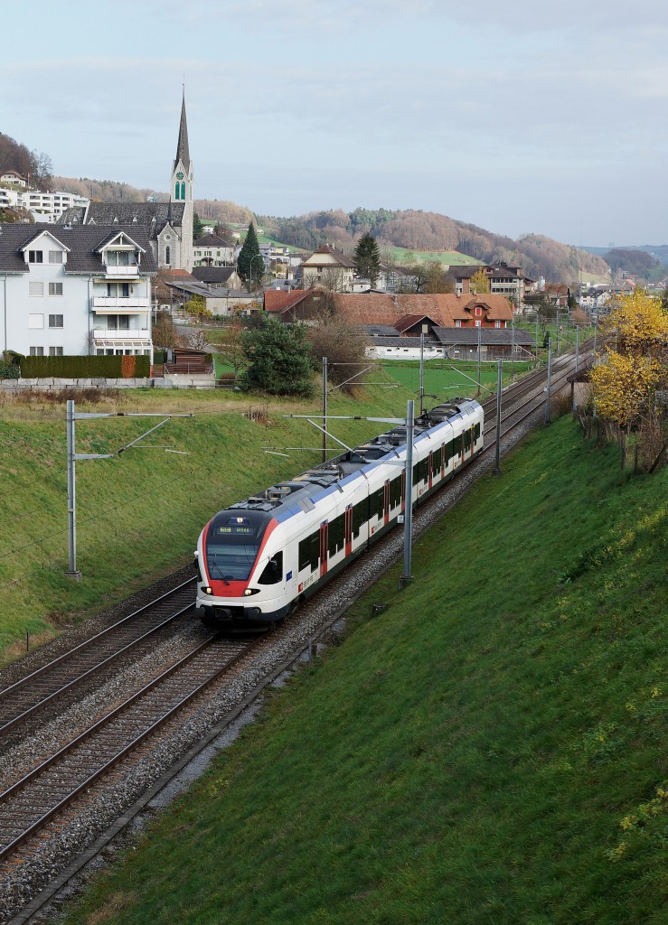 SBB: RE mit Triebzug 523 FLIRT nach Olten beim Passieren der Kirche Wauwil am 15. November 2015.
Foto: Walter Ruetsch