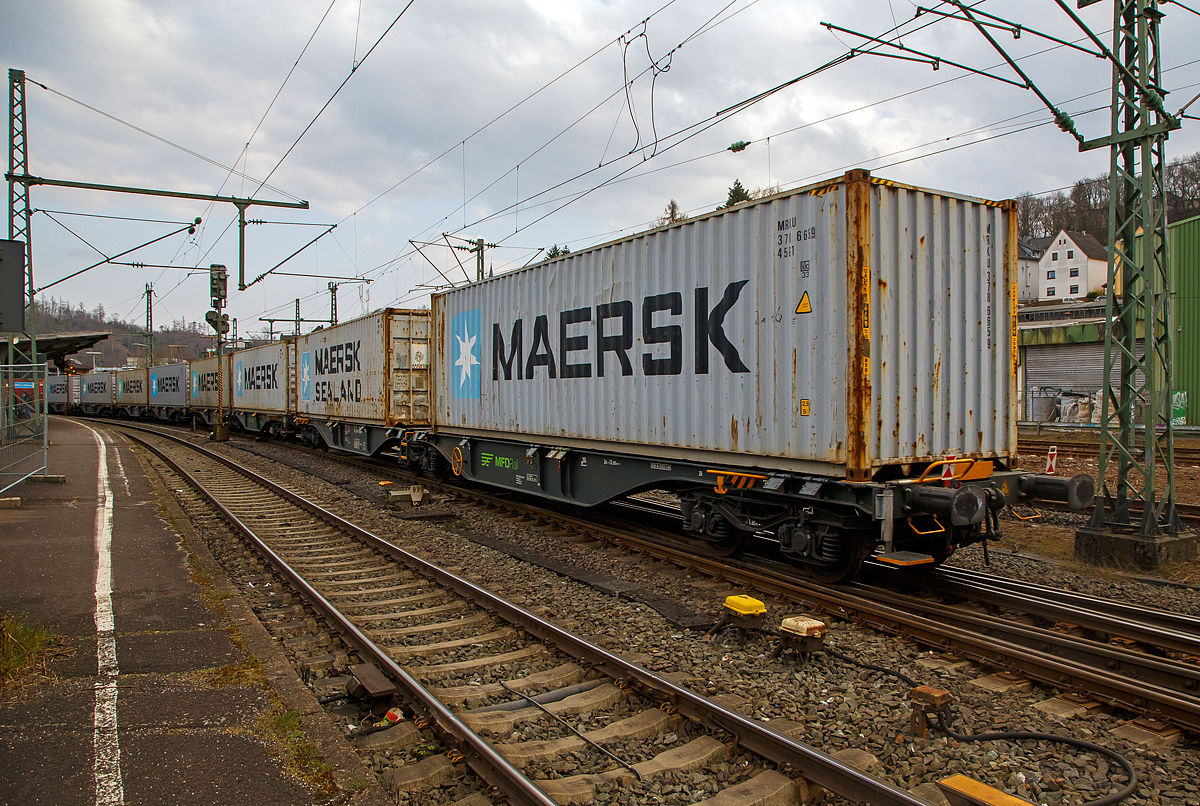 Sechsachsige Gelenk-Drehgestell Containertragwageneinheiten 90´ am 20.03.2022 im Zugverband bei der Zugdurchfahrt im Bf Betzdorf (Sieg), hier im Vordergrund der Wagen 37 80 4963 237-5 D-MFDR, der Gattung Sggmrss M4 (90´), der MFD Rail GmbH (Schweiz).

Diese Gelenkwagen mit sechs Radsätzen sind für den Transport von Großcontainern und Wechselbehältern vorgesehen. Auf den Außenlangträger des Wagens befinden sich für jede vorgesehene Ladeposition feste und klappbare Aufsetzzapfen zum Festlegen der Ladungseinheiten in verschiedenen Kombinationen. 

TECHNISCHE DATEN:
Spurweite: 1.435 mm
Länge über Puffer: 29.590 mm
Drehzapfenabstand: 2 x 12.025 mm
Achsabstand in den Drehgestellen: 1.800 mm
Drehgestelle: 3 x Y25 Ls-K
Laufraddurchmesser: 920 mm (neu)
Ladelänge: 2 x 13.800 mm
Höhe der Ladeebene über S.O.: 1.155 mm
Eigengewicht: 27.500 kg
Max. Zuladung bei Lastgrenze S: 107,5 t (ab Streckenklasse D)
Max. Zuladung bei Lastgrenze SS: 92,5 t (ab Streckenklasse C)
Max. Geschwindigkeit: 100 km/h (Lastgrenze SS und leer 120 km/h)
Kleinster befahrbarer Gleisbogen: R 75 m (Einzelwagen) / R 150 m (Zugverband)
Bremse: 2 x KE-GP-A (Max. 108 t)
Bremssohle: Jurid 816M 320
Feststellbremse: Ja
Intern. Verwendungsfähigkeit: TEN-GE
