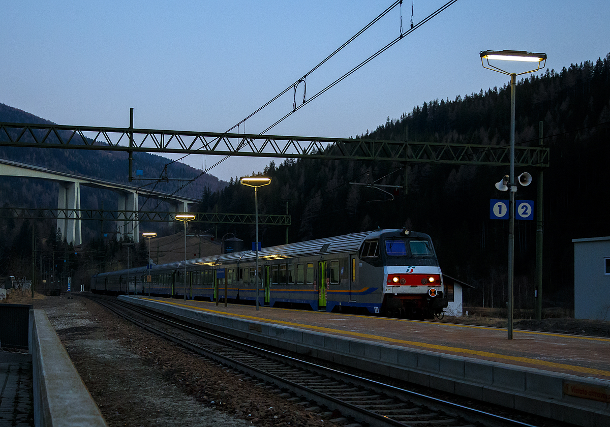 Sehr sauber und Steuerwagen voraus erreicht der Trenitalia Regional-Express RE 3462 (Verona Porta Nuova – Trento – Bozen – Brenner/ Brennero) am Abend des 27.03.2022 um 18:45 Uhr (noch ist Winterzeit) den Bahnhof Gossensaß/Colle Isarco, Schublok war die E.464.562.

An der Spitze ein 2. Klasse Reisezug- MDVC-Steuerwagen mit Gepäckabteil (MDVC steht für Medie Distanze Vestiboli Centrali, deutsch für Mittlere Entfernungen in Ballungsräumen) der Gattung npBD. Bei diesen Wagen handelt es sich um in Italien hergestellte Eisenbahnwaggons die speziell für den Einsatz für mittlere Entfernungen wie z.B. RE (Regionalexpress Züge). Das „TE“ (vorne unten zeigt das es sich um einen Steuerwagen vom Typ TE (Tipo TE) für E-Loks handelt.