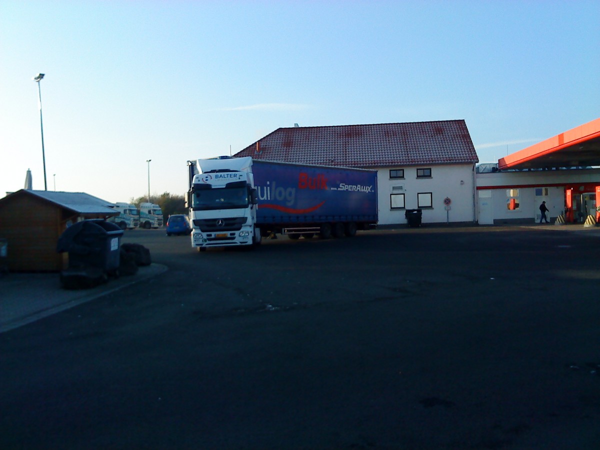 SZM Mercedes-Benz Actros mit Pritsche-Planen-Auflieger beim Verlassen des Autohofes in Grnstadt am 26.11.2013