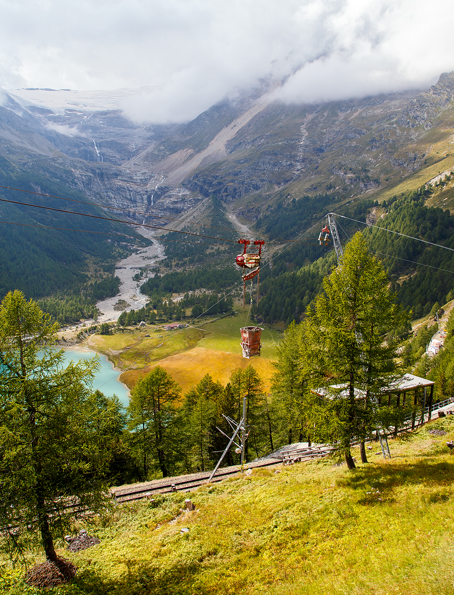 Unterhalb Alp Grüm werden die Alp Grüm der Berninabahn erneuert, daher gibt es eine Materialseilbahn von Alp Grüm hinab zu den Galerien, hier am 06.09.2021. So wird oben in Alp Grüm der Beton gemischt und dann mit der Seilbahn hinab gefahren. 

Die hier verwendete Bahn ist vom italienischen Seilbringungs-Spezialisten Seik (Truden). Der verwendete Wagen ist ein Seilkran vom Typ SFM 30/60.  In dem Seilkran befindet sich ein Verbrennungsmotor der das Hubwerk antreibt (dieser läuft nur bei der Hubbewegen) um wie hier den Betonkübel anzuheben und später wieder abzusenken. Die Hubkraft beträgt im Einzelzug 3t oder wie hier im Doppelzug mit dem Waagbalken 6t. Das Gesamtgewicht beträgt ca. 1t. Die Winde für das Zugseil kann nach Belieben (Bergseite – Talseite) platziert werden.