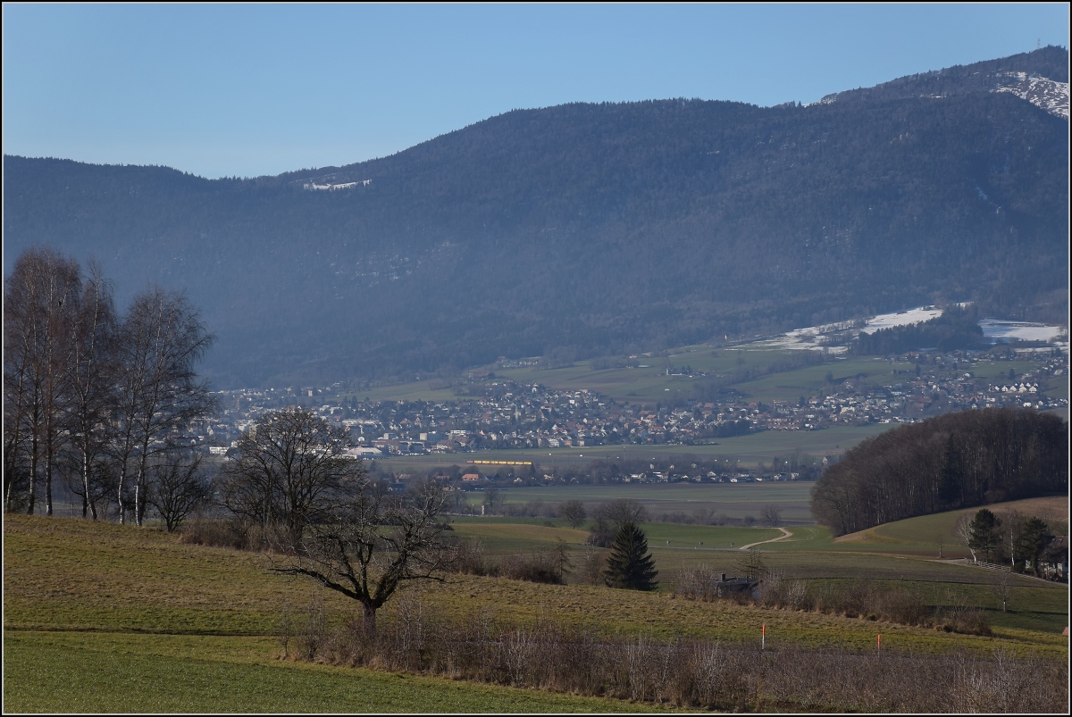 Viel Landschaft, wenig Zug am Jura.

Ein Postzug wird von einer Re 4/4 II auf der Jurasüdfusslinie nach Bettlach gezogen. Januar 2022. 