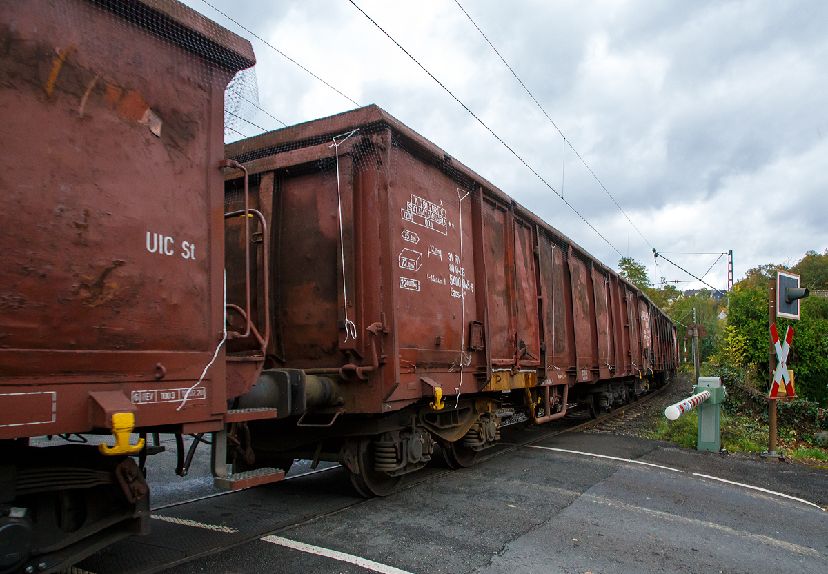 Vierachsiger offener Drehgestell-Güterwagen 31 80 5400 045-6, der Gattung Eanos-x 057, der DB Cargo AG am 22.10.2021 im Zugverband bei einer Zugdurchfahrt in Kirchen (Sieg), hier beim BÜ km 121,192.

Der Eaos-x 057 entstanden 1999 bis 2003 durch Festlegung der Stirnklappen an Eas 066-Wagen (ex DR Eas). Vorgesehen war zunächst die Umrüstung von 1.000 Wagen, die als stirnkippfähige Fahrzeuge nicht mehr benötigt wurden. Damit sollen Einsparungen für die Stirnklappen-Unterhaltung erzielt werden. Hier sieht man sehr gut dass die Stirnklappe verschweißt wurde.

Gebaut wurden diese Wagen 1981/82 von den französischen Herstellern Arbel-Fauvet-Rail und ANF-Industrie für die DR. Es waren die ersten offenen Drehgestellwagen nach UIC-Standard in der DDR.

Die ersten etwa 500 Fahrzeuge behalten bei der Umrüstung ihre jeweils zwei Doppeltüren je Wagenseite, bei allen folgenden Serien wird auf beiden Wagenseiten auf eine dieser Türen verzichtet, d.h. diagonal gegenüberliegende Türen sind entfernt und die Ausschnitte mit Blechen verschlossen. Ab etwa 2002 werden weitere 650 Eas 066 zu Eaos-x 057 umgerüstet. 

TECHNISCHE DATEN:
Spurweite: 1.435 mm (Normalspur)
Achsanzahl: 4 in zwei Drehgestellen
Länge über Puffer: 14.040 mm
Drehzapfenabstand: 9.000 mm
Achsabstand im Drehgestell: 1.800 mm
Ladelänge: 12.800 mm
Ladebreite:  2.760 mm
Ladehöhe: 2.100 mm
Ladefläche: 35,3 m²
Laderaum:  72,0 m³
Türöffnung: 2 Stück 1.800 × 1.900 mm
Höchstgeschwindigkeit: 100 km/h (beladen) / 120 km/h (leer)
Maximales Ladegewicht ab Streckenklasse C: 57,5 t 
Eigengewicht: 22.400 kg
Kleinster bef. Gleisbogenradius: R 35 m
Bremse: KE-GP (LL)
Handbremse: Teilweise Fbr.
Intern. Verwendungsfähigkeit: RIV