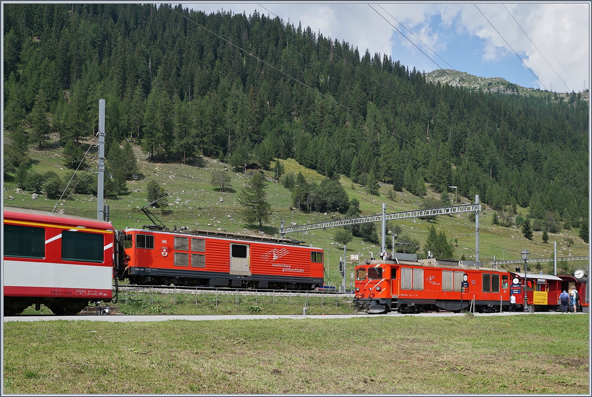 Während die MGB Gm 4/4 61 im DFB Bahnhof von Oberwald rangiert, fährt im MGB Bahnhof ein Regionalzug Richtung Andermatt aus..

31. August 2019