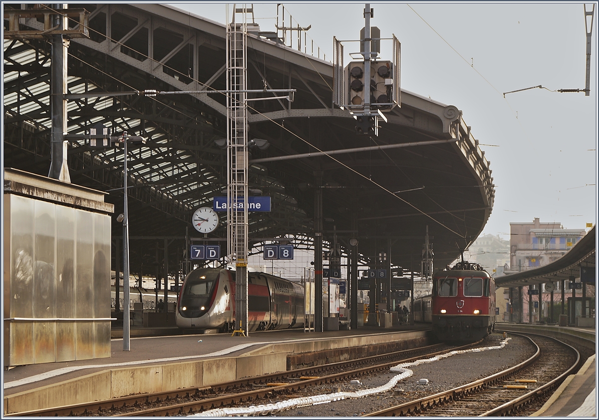 Während die SBB RE 4/4 II 11194 (und am Zugschluss die Re 4/4 II 11197) mit ihrem Dispozug einem IR 90 ersetzen wartet unter der Bahnhofshalle von Lausanne ein TGV Lyria auf die Abfahrt. 

25. Jan. 2020