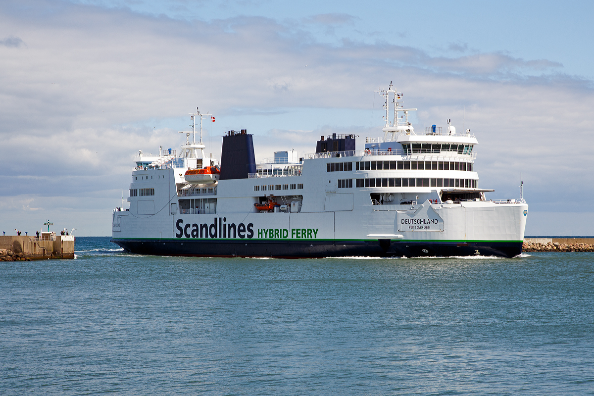 
Was hat ein Schiff mit Bahnbildern zu tun, ganz einfach es ist eine Eisenbahnfähre.
 
Die Deutschland fährt am 15.06.2015 in den Fährhafen Puttgarden ein.

Die Deutschland  ist eine kombinierte RoRo- und Eisenbahnfähre der Scandlines Deutschland GmbH, die seit 1997 auf der Vogelfluglinie eingesetzt wird.

Im Gegensatz zu ihren Vorgängern hat die Deutschland nur noch ein Gleis zur Aufnahme eines ICE TD oder zweier DSB MF. Der Transport von Güterwagen ist auf der Vogelfluglinie eingestellt worden. Das Schiff macht mit Haken in Höhe des Eisenbahndecks automatisch in den verbreiterten Fährbetten fest. Weil die Doppelendfähre die vorher üblichen Wendemanöver nicht mehr fahren muss, konnte die Fahrzeit um 25 % gekürzt werden und beträgt nur noch 45 Minuten.

Technische Daten:
Flagge: Deutschland
Schiffstyp 	Doppelendfähre
Länge über alles: 142,0 m
Breite: 24,78 m
Tiefgang: max. 6,0 m
Maschine (Dieselelektrischer Antrieb): 3 × MaK 8M32 und 2 MaK 6M32 Dieselmotoren mit Drehstromgeneratoren
Maschinenleistung: 15.840 kW (21.536 PS)
Dienstgeschwindigkeit: 18,5 kn (34 km/h)
Propeller: 	4 Propellergondeln
Transportkapazitäten
Zugelassene Passagierzahl: 1.200
Ladevolumen: 1 ICE TD oder 2 DSB MF sowie 40 Lkw oder 156 Pkw auf 625 m Länge plus 118 Pkw auf dem Autodeck
