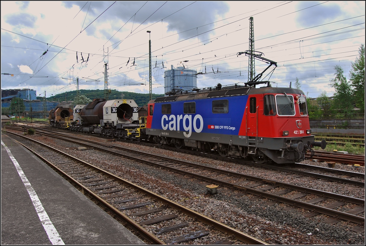 Werksverkehr fernab der Schweiz. Re 4/4 II 11390 transportiert zwei Torpedopfannenwagen mit Flüssigeisen von der Eisenhütte (im Hintergrund) in Völklingen nach Dillingen. Juli 2014