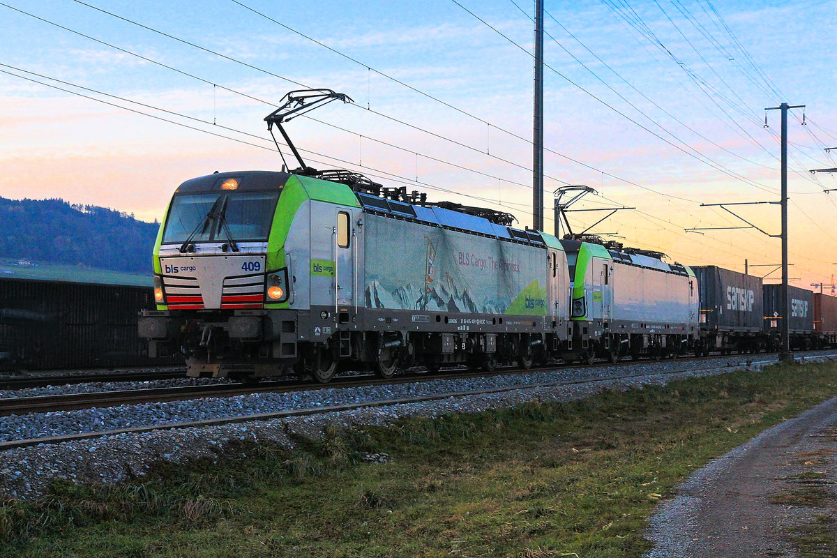 Zugsvielfalt bei Sonnenuntergang an der Bahnstrecke Bern-Thun: Containerzug, geführt von den beiden BLS Vectron Loks 475 409 und 475 416. Wichtrach, 23.Nov.2020 