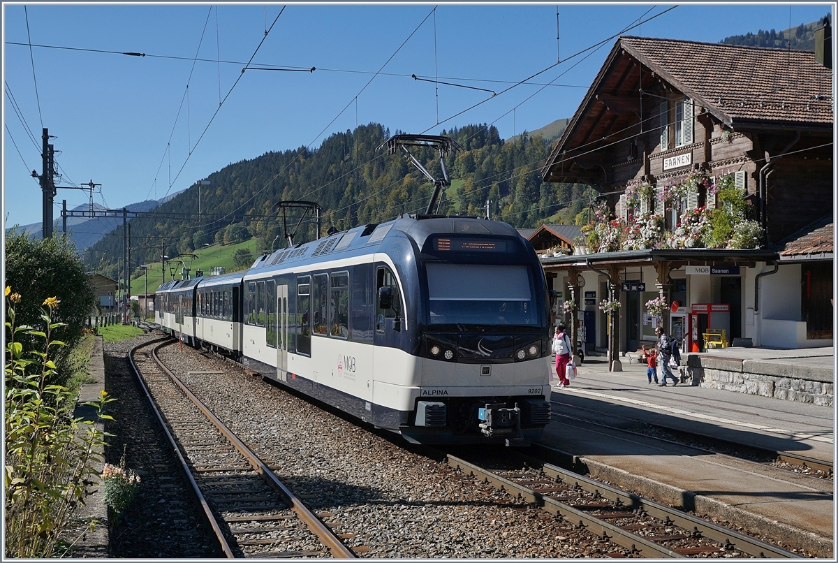 Zwei MOB Alpina Triebwagen (ABe 4/4 und Be 4/4 Serie 9000) sind mit zwei Zwischenwagen als Regionalzug von Zweisimmen nach Montreux unterwegs und halten in Saanen.
Beachtenswert: der Blumengeschmückte Bahnhof von Saanen. 

5. Okt. 2018