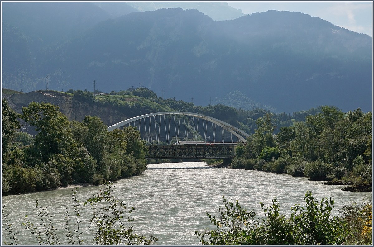 Zwischen Bex und St-Maurice berquert die Strecke Lausanne Birg die Rhone. Die alte Gittereisenbrcke wird nun durch eine sehr gefllige und unbersehbare Neukonstruktion ersetzt.
Zu Zeit ist die alte Brcke schon nicht mehr in Betrieb und der Verkehr verluft einspurig ber die neue Brcke, wobei vor und nach der Brcke das nrdliche Gleis, dann auf der Brcke das Sdliche Gleis benutzt wird, so dass die Brcke noch verschoben werden muss.
Leider ist es nicht einfach, einen einigermasen guten Fotostandpunkt zu finden. 
Das Bild zeigt beiden Brcken von Sden und (teilweise zu sehen) einen SBB ETR 610 auf dem Weg Richtung Lausanne.
19. August 2016   