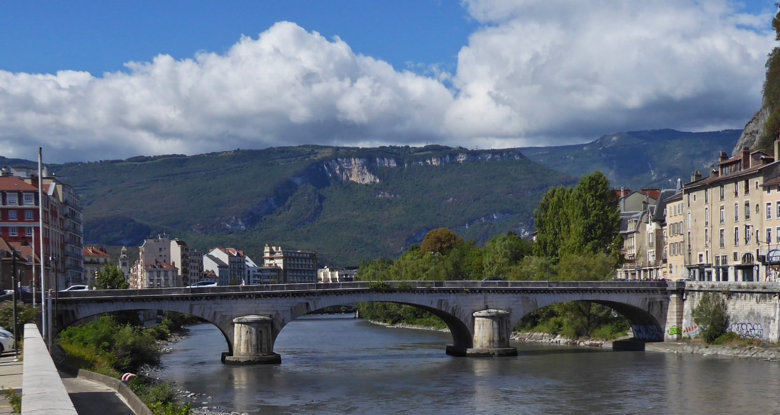 Blick bei der Seilbahn über die Isère in Grenoble auf den „Pont Maurice Gontard“ mit der Bergwelt im Hintergrund. 09.2022