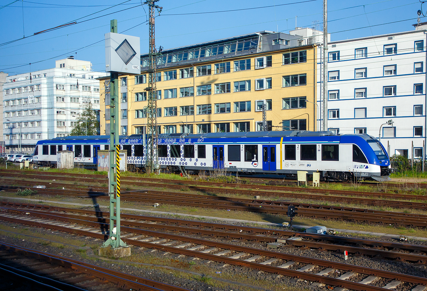 Das ist Klimaschutz....
Der zweiteilige (mit Wasserstoff fahrende) Brennstoffzellentriebzug 554 110 / 554 610 (90 80 0554 110-1 D-TLS / 90 80 0554 610-0 D-TLS), ein ALSTOM Coradia ILint 54, vom Fahrzeugmanagement Region Frankfurt RheinMain GmbH (fahma), betrieben durch die Regionalverkehre Start Deutschland GmbH, ist am 21.04.2023 beim Hauptbahnhof Frankfurt am Main abgestellt, aus einem fahrenden Zug heraus (durch die Scheibe) fotografiert.

Der ILint 54 wurde 2022 von ALSTOM Transport Deutschland GmbH (vormals LHB) in Salzgitter-Watenstedt unter der Fabriknummer D041461-010 gebaut.

Die Regionalverkehre Start Deutschland GmbH betreibt seit Dezember 2022 RMV-Taunusnetz. Das Besondere an diesem Netz (RB 11, RB 12, RB 15 und RB 16) ist, hier kommt ab der Inbetriebnahme sukzessive die grte Wasserstoffzugflotte der Welt auf die Schiene. Letztendlich werden im gesamten Netz 27 wasserstoffbetriebene Fahrzeuge vom Typ Coradia iLint des Herstellers Alstom zum Einsatz kommen.  Die fahma hat die Zge 2019 bestellt und stellt diese dem Betreiberunternehmen zu Verfgung. Die neuen zweiteiligen Triebzge lsen die dort fahrenden Zge des Typs Lint 41/H der fahma ab, die auf einer anderen Strecke weiter eingesetzt werden. Ausgemustert wird hingegen der Zugtyp VT/2E der HLB bzw. des Verkehrsverbands Hochtaunus.

Die fahma hat neben der Beschaffung der Zge auch die sichere Versorgung mit Wasserstoff, die Instandhaltung und das Vorhalten von Reservekapazitten fr die kommenden 25 Jahre beauftragt. Die Versorgung mit Wasserstoff bietet Alstom in Kooperation mit der Infraserv GmbH & Co. Hchst KG an. Dabei befindet sich die Tankstelle auf dem Gelnde des Industrieparks Frankfurt-Hchst.

Der Coradia iLint ist weltweit der erste Personenzug, der mit einer Wasserstoff-Brennstoffzelle betrieben wird, die elektrische Energie fr den Antrieb erzeugt. In der Traktionsbatterie werden der vorbergehend berschssig erzeugte Strom sowie die bei Bremsvorgngen zurckgewonnene Energie zwischengespeichert. Die umfangreich und komfortabel ausgestatteten Triebfahrzeuge sind so leise wie ein Elektro-Triebfahrzeug und emissionsfrei, weil sie lediglich Wasserdampf und Wrme an die Umwelt abgeben.

Die Wasserstofftriebzge:
Ein Triebwagen besteht aus zwei Wagenteilen, die jeweils auf zwei Drehgestellen (je ein Trieb- und ein Laufdrehgestell) ruhen. 

Die Energieerzeugung geschieht durch eine teilautonome Wasserstoff-Brennstoffzellenanlage zur Erzeugung elektrischer Energie. Die Antriebsleistung erfolgt durch 2 Drehstrom-Asynchronmotoren mit einer Leistung je 380 KW. In der Traktionsbatterieanlage  (Lithium-Ionen-Batterien) werden der vorbergehend berschssig erzeugte Strom, sowie die bei Bremsvorgngen zurckgewonnene Energie zwischengespeichert. Die maximale (volle) Treibstofftankkapazitt betrgt 2 x 125 Kg Wasserstoff bei 350 bar und 15 C, hrt sich wenig an, aber Wasserstoff hat eine sehr hohe Energiedichte. So erbeben die 125 kg H x 33 kWh/kg stolze 4.125 kWh. Fr die gleiche Energieleistung wre z.B. Erdgas 8x schwerer. Zur Veranschaulichung ein beladener Lkw bentigt ca.  50-70 kg Wasserstoff, um 500 bis 600 km weit zu fahren.

Eine Mehrfachtraktion von bis zu 4 Fahrzeugen ist mglich. Fr eine Fremdeinspeisung sind beidseitig auen Anschlsse  fr 3x400V AC 32A vorhanden. An den Einstigen sind fr die Spaltberbrckung am Bahnsteig Schiebetritte vorhanden. Fr Rollstuhlfahrer werden zwei ausklappbar Rampen mitgefhrt. Ein Triebwagen hat eine Klimaanlage getrennt fr Fahrgastraum und Fhrerraum, ein Fahrerassistenzsystem, ein Fahrzeugdiagnosesystem, sowie ein automatisches Fahrgastzhlsystem. Im Innenraum ist eine Toilette (Universal-WC) mit geschlossenem System eingebaut, zudem sind ein Fahrgast-WLAN, Laptop-Steckdosen an 50 % der Festsitze, ein Fahrgast-Informationssystem (ber LCD-Flachbildschirme) und eine Videoberwachung des ganzen Innenraumes vorhanden.

Die Befrderungskapazitt eines Treibwangens:
Ein Treibwagen hat insgesamt 160 Sitzpltze, davon 122 feste Sitze in der 2. Klasse und 16 in der 1. Klasse, zudem 22 Klappsitze. Rechnerisch (4 Pers./m) sind maximal 144 Stehpltze mglich. Zudem sind 2 Rollstuhl- und 12 Fahrradabstellpltze vorhanden, dadurch reduzieren jedoch (je nach Anzahl) die Klappsitze und Stehpltze. Bei voller Auslastung betrgt das Betriebsgewicht ca. 107 t. 

TECHNISCHE DATEN:
Spurweite: 1.435 mm
Achsfolge: B’2’+2’B’
Lngsdruckfestigkeit:1.500 kN
Fahrzeuglnge ber Kupplung:  54.270 mm
Fahrzeugbreite: 2.730 mm (3.030 mm mit ausgefahrenem Schiebetritt)
Maximale Fahrzeughhe (ber SO):  4.300 mm
Einstieghhe (ber SO): ca. 810 mm 
Fubodenhhe im Hochflurbereich: 1.190 mm
Anzahl der Tren je Seite: 4 (1 x mit ausklappbarer Rollstuhlrampen)
Lichte Weite x Hhe der Tren: 1.300 x 2.015 mm
Installierte Leistung: 2 x380 kW
Leistungsbertragung: elektrisch
Motoren: 2 Drehstrom-Asynchronmotoren
Hchstgeschwindigkeit: 140 km/h 
Maximale Streckenneigung:  40 ‰
Betriebsgewicht: ca. 107 t
Maximale Achslast: 18 t 
Treibstofftankkapazitt: 2 x 125 Kg Wasserstoff bei 350 bar und 15 C
Bremsen: Wellenscheibenbremsen,ED- und EP-Bremsanlage, indirekte und Mg-Bremse, Feststellbremsen 
Kupplung: Mittelpufferkupplung Schaku Typ 10
kleinster befahrbarer Gleisbogen: R 150 m (Normal) / R 100 m (Werkstatt)

Der Coradia iLint ist weltweit der erste Personenzug, der mit einer Wasserstoff-Brennstoffzelle betrieben wird, die elektrische Energie fr den Antrieb erzeugt. Dieser emissionsfreie Zug ist geruscharm und gibt lediglich Wasserdampf und Kondenswasser ab. Der iLint zeichnet sich durch die Kombination verschiedener innovativer Konzepte aus: saubere Energieumwandlung, flexible Energiespeicherung in Batterien sowie smartes Management von Antriebskraft und verfgbarer Energie. Gezielt entwickelt fr den Einsatz auf nichtelektrifizierten Strecken, ermglicht er einen sauberen, nachhaltigen Zugbetrieb unter Beibehaltung einer hohen Leistung.  

Persnlicher Verbesserungsvorschlag:
Vielleicht knnte man unter Oberleitungen direkt elektrisch fahren. Ja dafr braucht der Zug nicht nur einen Stromabnehmer, sondern auch einen Trafo usw., aber Reichweite wrde erhht. 

