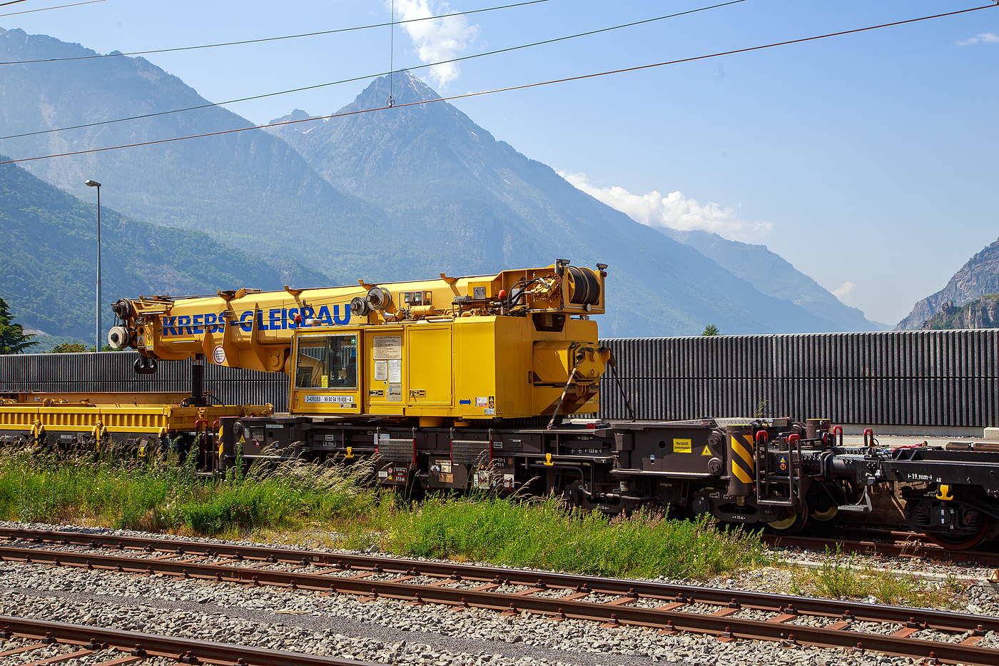 Der 130 t Eisenbahnkran D-KREBS 99 80 9419 008-4, ex 97 82 54 501 17-1, ein GOTTWALD GS 130.06 TT Gleisbauschienenkran der Krebs GmbH & Co. KG, Bingen am Rhein (D) / Bern (CH) ist am 26.05. 2023 beim Bahnhof Martigny, in Transportstellung mit dem Gegenlastwagen 33 88 3936 639-4 B-Krebs der Gattung Rels und dem Schutzwagen auslegerseitig 99 80 9383 003-7 D-Krebs der Gattung Rgs, abgestellt.