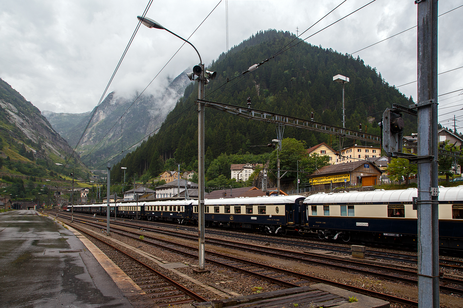 Der „König der Züge“ der Orient-Express, oder für mich der Zug der Züge. Wir hatten am Vortag bei der Ankunft im Hotel davon erfahren, das der VSOE am nächsten Tag durchfährt, so haben wir unsere Weiterfahrt über den Gotthardbahn nach Locarno und weiter mit der Centovallibahn nach Domodossola, etwas verschoben. 

Der VSOE - Venice Simplon-Orient-Express von Amsterdam über Brüssel und Paris nach Venedig hat am 02. August 2019 leider bei Regen, gezogen von einer SBB Re 8/8 (Doppeltraktion der Re 4/4 11194 und Re 4/4 11156), den Bahnhof Göschenen erreicht und steht so nun vor dem Nordportal des 15 km langen Gotthard-Scheiteltunnels. Hier fährt er aber nicht, wie es im Namen steht, durch den Simplon, sondern über den Gotthard. Der Orient-Express bestand aus einem Zug mit 18 Wagen, meinst waren es modernisierte historische ehemalige CIWL-Wagen. Ob es auch einen „Mord im Orient-Express“ gab? Das kann ich nicht sagen, hatte aber gehört das man wohl einen im Zug nachspielte.

Wer kennt den Film nicht „Mord im Orient-Express“ nach dem Roman von Agatha Christie aus dem Jahr 1934. Wo der berühmte belgische Privatdetektiv Hercule Poirot den Mord an einem reichen Amerikaner untersucht, der im berühmtesten Zug der Welt reist.

Der Venice Simplon-Orient-Express (abgekürzt VSOE), verkehrt seit 1982. Der Luxuszug wird von der Firma Belmond Ltd. betrieben. Der Zug besteht aus historischen Wagen der Compagnie Internationale des Wagons-Lits (CIWL). Es werden Fahrten in Form von Schienenkreuzfahrten über verschiedene europäische Strecken angeboten, darunter auch die historischen Strecken des früheren Simplon-Orient-Express und des Orient-Express.

