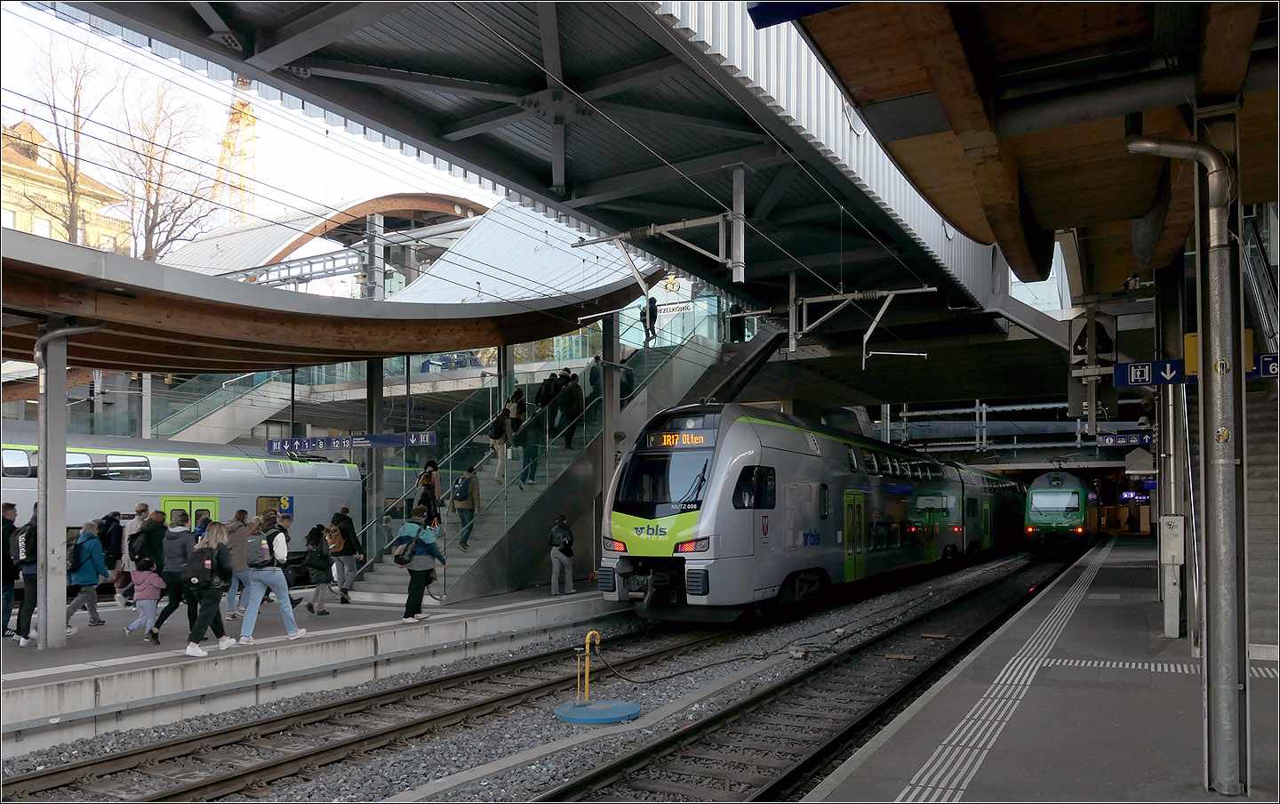 Der Bahnhof Bern - 

Im westlichen Bahnhofsbereich wurden 2004 die Bahnsteige verlängert und ein neuer Zugang im Bereich der Schanzenbrücke geschaffen. Da die Bahnsteigdächer wellenförmig über diese neue Zugangsbrücke hinweg geführt sind, wurde dieser Zugang 'Welle' genannt.

Derzeit wird unterhalb der Bahnsteige ein neuer großer viergleisiger Tunnelbahnhof für die RBS gebaut. Damit dafür oben Bahnsteiggleise gesperrt werden können wurde der Bahnsteig an Gleis 9 und 10 auf 785 Meter verlängert um zwei lange Züge hintereinander halten lassen zu können.

Dafür wurde 2019 eine provisorischer Fußgängersteg ähnlich einer Fluggastbrücke mit Anschluss an die Welle gebaut um die Fahrgäste unabhängig vom Bahnsteig einen weiteren Weg zum verlängerten Bahnsteig führen zu können. Dieser Steg ist hier über den Gleisen zu sehen.

07.03.2025

