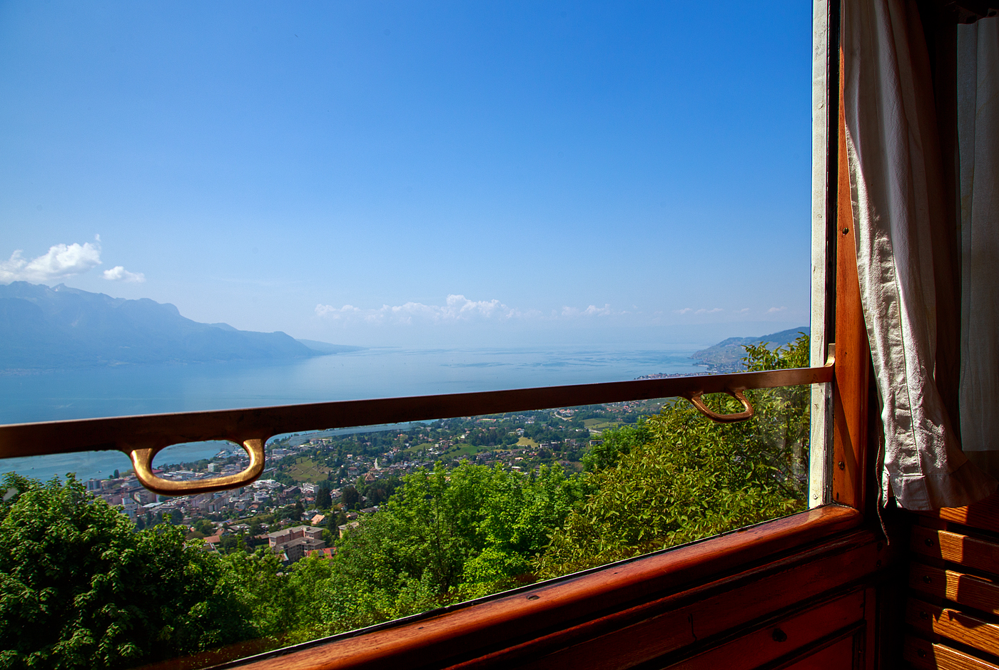 Der Blick aus unserem Zug (dem MOB BCFe 4/4 11 der Museumsbahn Blonay–Chamby) hier am 27.05.2023 im Bahnhof Chamby, auf den Genfersee / Lac Léman.