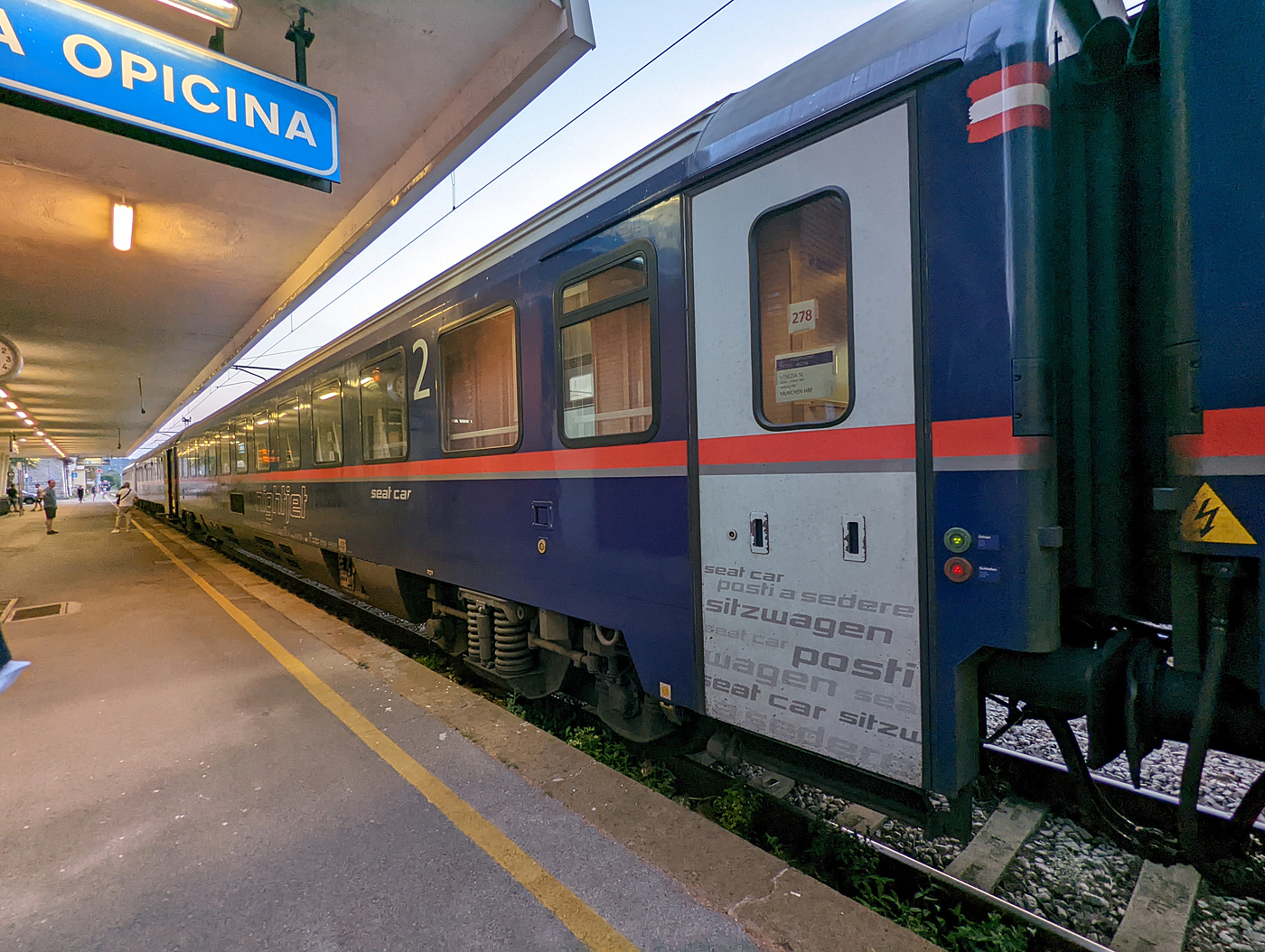 Der Bmz Sitzwagen A-ÖBB 78 81 21-91 153-6, als Wagen Nr. 278 im Zugverband des ÖBB Nightjet EN 236 / 40236 von Venezia SL über Udine, Villach und Salzburg nach München. Hier am Abend des 24 Juli 2022 beim Grenzkontrollenhalt im italienischen Grenzort Villa Opicina (nach Slowenien).