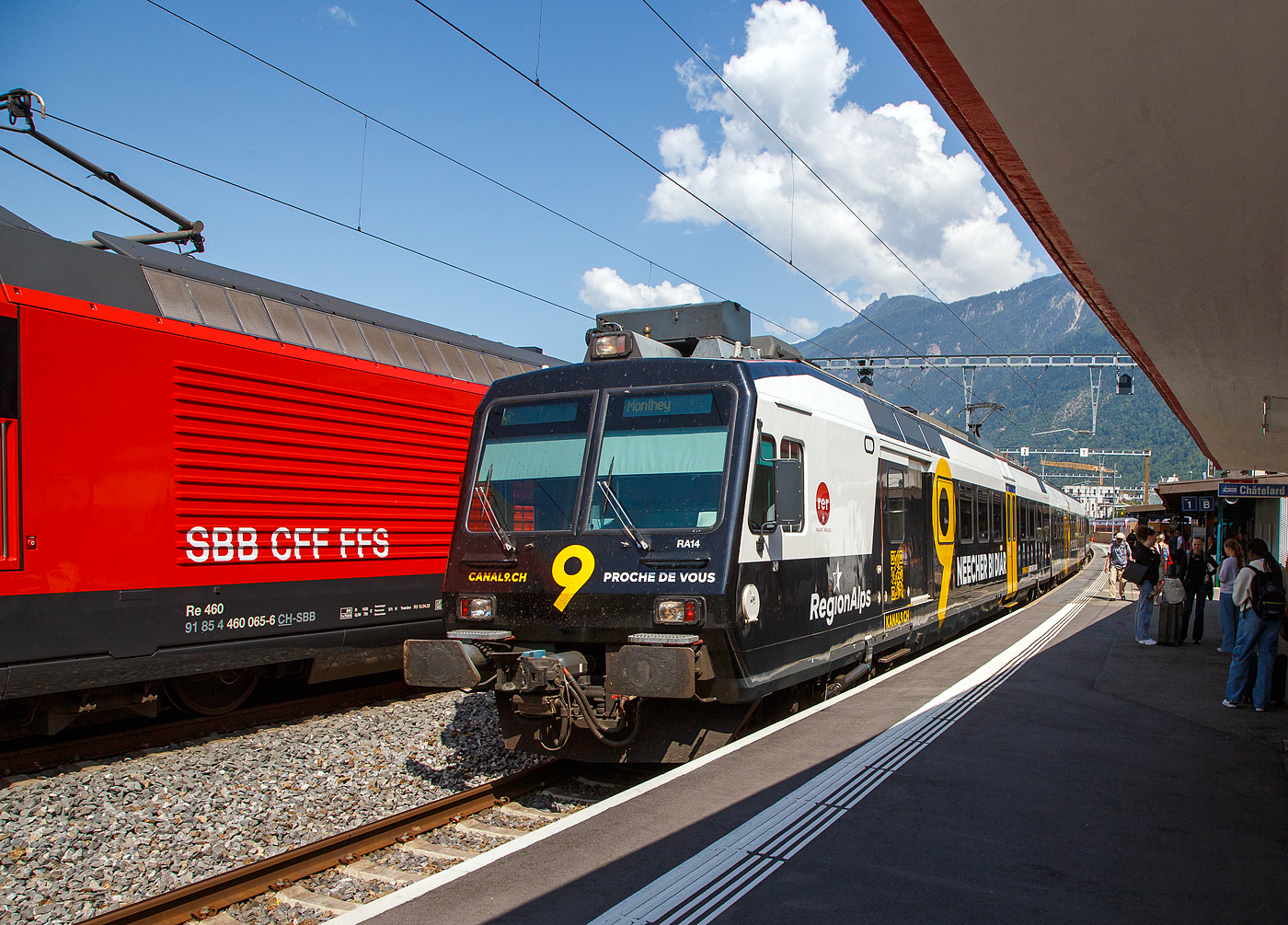 Der dreiteilige NPZ Domino RA14 der RegionAlps, mit der Vollwerbung für den Walliser Fernseh-Sender Kanal 9, verlässt am 26.Mai 2023, als Regionalzug nach Monthey den Bahnhof Martigny.

Der NPZ Domino besteht aus den Triebwagen RBDe 560 DO RA 94 85 7 560 414-5, dem 2.Klasse Wagen B NPZ DO RA 50 85 29-43 414-6 und dem 1./2. Klasse Steuerwagen ABt NPZ DO RA 50 85 39-43 954-9 CH-RA (ex SBB RBDe 560 276, ex SBB B 29-43 181 und ex SBB ABt 39-43 869).

Die Regionalps (RA) ist ein Eisenbahnverkehrsunternehmen im Kanton Wallis, mit Sitz in Martigny hat. Eigentümer derim Jahr 2003 gegründete Gesellschaft  sind die Schweizerischen Bundesbahnen (SBB) mit 70 %, die Transports de Martigny et Régions (TMR) mit 18 % und der Kanton Wallis mit 12 %. Die RA betreibt den Regionalverkehr vor allem im Rhonetal zwischen dem Ostufer des Genfersees und Brig. Inzwischen gehören Regionalps 16 dreiteilige NPZ Domino (Trieb-, Zwischen- und Steuerwagen ex SBB) und 4 RABe 525 NINA (ex TMR).
