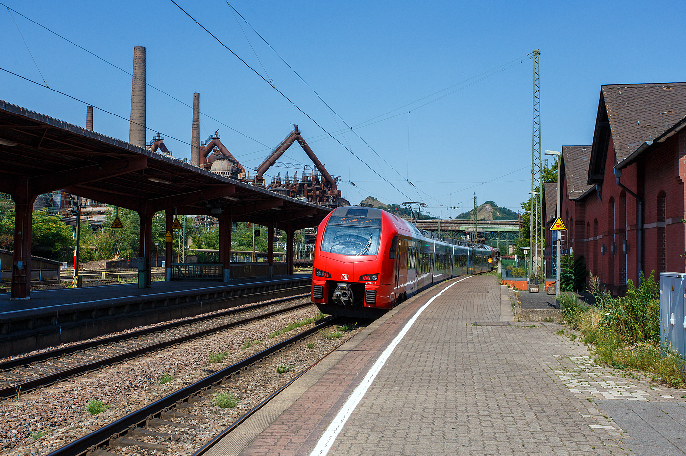 Der fünfteilige SÜWEX Stadler FLIRT 3 – 429 114 / 429 614, als RE 1  Südwest-Express  (Kaiserslautern – Trier – Koblenz), verlässt am 01 Juli 2025 den Bahnhof Völklingen und fährt weiter in Richtung Dillingen. Ich finde das neue Farbdesign der SÜWEX (Südwest-Express), mit den nun roten Triebwagenköpfen, ist für mich gelungener als das alte Farbdesign.

Im Hintergrund das Ziel unserer Reise an diesem Tag, das Weltkulturerbe Völklinger Hütte. Die Völklinger Hütte ist weltweit das einzige Eisenwerk aus der Blütezeit der Industrialisierung, das vollständig erhalten ist. Seit 1994 zählt es zum UNESCO-Weltkulturerbe.