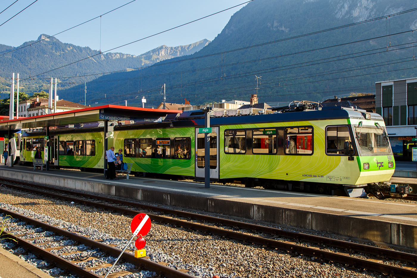 Der tpc AOMC / ASD) Beh 4/8 591, ein elektrischer Doppeltriebwagen für den gemischten Zahnrad- und Adhäsionsbetrieb steht im Bahnhof Aigle als ASD Regionalzug R 24 zur Abfahrt nach Les Diablerets bereit. Wobei den Zahnradantrieb („h“) brauch er auf der 23,3 Kilometer langen Strecke der ASD (Aigle–Sépey–Diablerets) nicht, denn sie ist eine reine Adhäsionsbahn und führt von Aigle über Le Sépey nach Les Diablerets.

Die beiden Doppeltriebwagen Beh 4/8 591–592 wurden 2001 von Bombardier, ex Vevey ACMV (Wagenkasten), Stadler (Drehgestelle/Zahnradtechnik) und Adtranz (Elektrik) gebaut und an die tpc für den Betriebsteil AOMC geliefert. Damals war dort noch unter 950 V Gleichspannung (DC) und mit dem Zahnstangensystem Strub gefahren. 

Im Sommer 2016 wurde die AOMC Strecke umfassend modernisiert. Dabei wurden die Zahnstangenabschnitte vollständig erneuert und das bisherige Zahnstangensystem Strub durch das Zahnstangensystem Abt ersetzt. Die Fahrleitungsspannung von 950 V wurde nun auf 1500 V Gleichspannung (DC) erhöht. Somit besitzen alle ab Aigle verkehrenden Strecken der TPC das gleiche Zahnstangensystem (wobei die ASD keine Zahnstange hat) und die gleiche Spannung. Der Verkehr wird nun meist vollständig mit den neu abgelieferten Beh 2/6 541–547 abgewickelt. Von den bestehenden Triebfahrzeugen der AOMC wurden einzig die beiden im Jahr 2001 gelieferten Doppeltriebwagen Beh 4/8 591–592 an das neue Zahnstangen- und Stromsystem angepasst.

So erfolgte im Jahr 2016 bei Stadler der Umbau der beiden Beh 4/8 591–592 auf 1.500 V DC mit neuem Umrichter, die Trieb- und Bremszahnräder wurden (von Strub zu Abt) ersetzt. Die Fahrmotoren konnten ohne eine Neuwicklung beibehalten werden.

Vermutlich können die Doppeltriebwagen aber nicht auf den Zahnstangenabschnitten der AL (Aigle–Leysin-Bahn) fahren, denn diese haben eine Neigung bis zu 230 ‰, die AOMC (wofür die Treibwagen gebaut wurden) hat ja eine maximale Neigung von 135 ‰. 

TECHNSCHE DATEN:
Baujahr: 2001 (Umbau 2016)
Spurweite: 1.000 mm (Meterspur)
Achsfolge: Bo'zz 2' + 2' Bo'zz
Zahnradsystem:  Abt (bis 2015 Strub)
Länge über Puffer : 35.200 mm
Eigengewicht: 58,5 t (bis 2015 55,1t)
Zul. Höchstgeschwindigkeit (Adhäsion): 80km/h 
Zul. Höchstgeschwindigkeit (Zahnradbetrieb): 30 km/h bei Bergfahrt 
Max. Neigung : 135 ‰
Sitzplätze: 96 
Stehplätze: 70 
Stromsystem: 1.500 V DC (Gleichstrom) (950 V DC bis 2015)
Stromabnehmer: 2
Bremse: Frein P + Mg-A
