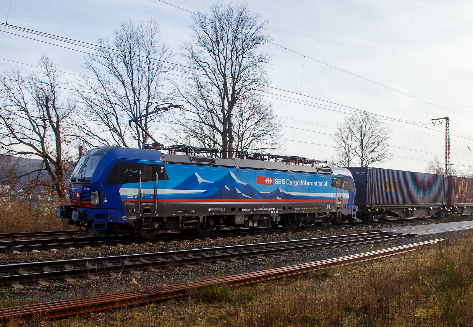 Die an die SBB Cargo International AG vermietete 193 530-3  Po  (91 80 6193 530-3 D-SIEAG) der SüdLeasing GmbH (Stuttgart, eingestellt in Deutschland durch Siemens) fährt am 22.02.2023, mit einem Containerzug, durch Wilnsdorf-Rudersdorf (Kr. Siegen) in Richtung Siegen. 

Der SIEMENS Vectron MS wurde 2019 von Siemens Mobilitiy in München-Allach unter der Fabriknummer 22726 gebaut. Eigentümer ist die Südleasing GmbH in Stuttgart (LBBW-Tochter) die 20 dieser Loks an die SBB Cargo International vermietet hat, eingestellt sind sie in Deutschland durch die Siemens Mobilitiy. 

Diese Mehrsystem-Loks sind für den Einsatz auf dem Rhein-Alpen-Korridor vorgesehen und sind für den Betrieb in Deutschland, Österreich, Schweiz, Italien und den Niederlanden (D/A/CH/I/NL) ausgelegt. Sie verfügen über eine Leistung von 6,4 MW (160 km/h) und sind neben den nationalen Zugsicherungssystemen mit dem Europäischen Zugsicherungssystem (ETCS) ausgestattet.
