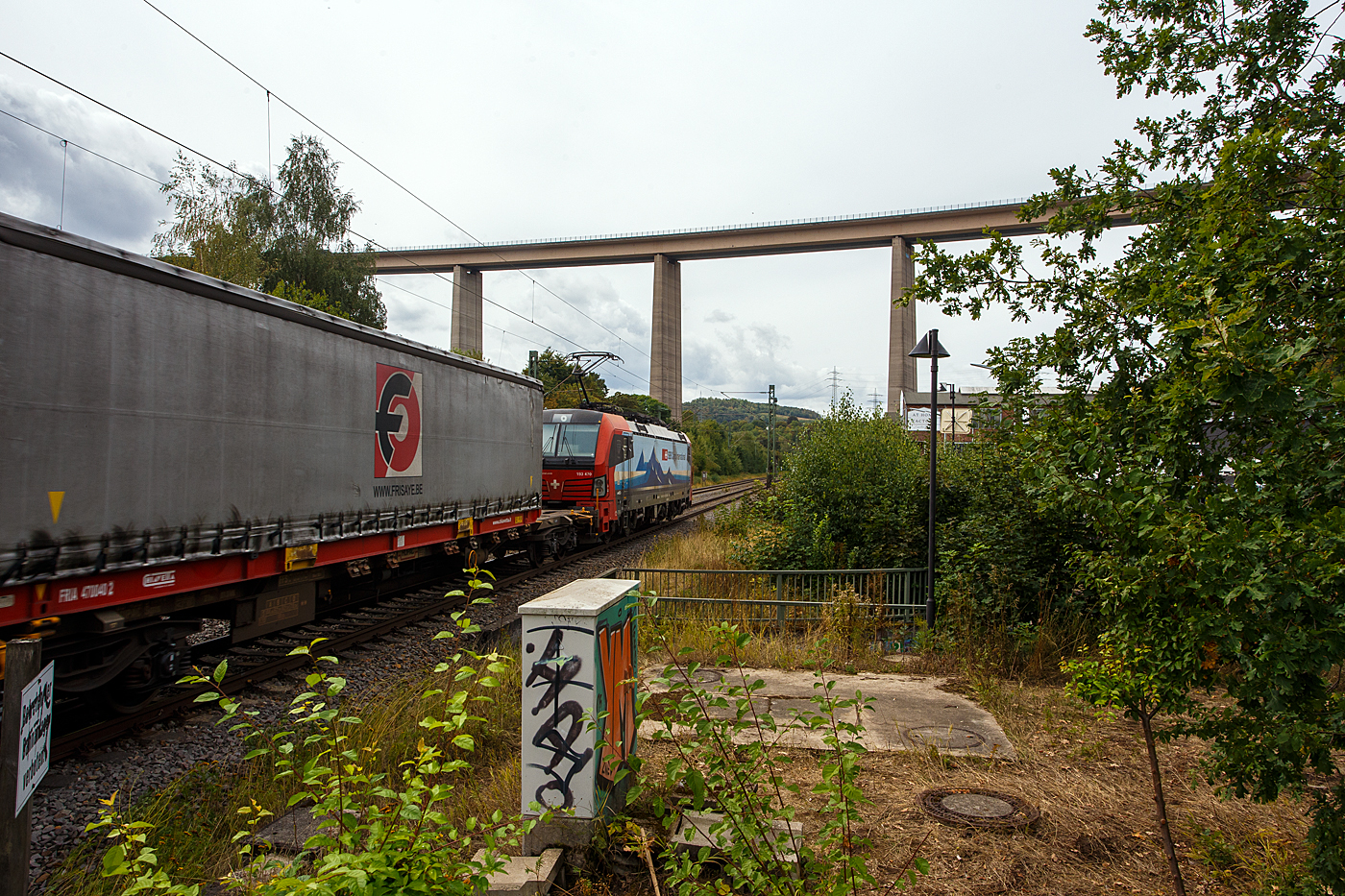 Die an die SBB Cargo International vermietete Siemens Vectron MS 193 470 „Freiburg“ (91 80 6193 470-2 D-SIEAG) f�hrt am 21 August 2026 mit einem HUPAC-Zug durch Siegen-Eiserfeld in Richtung K�ln, hier �berquer sie wie so oft auf der Siegstrecke die Sieg.  Im Hintergrund die 105 m hohe Siegtalbr�cke der Autobahn A45 (Sauerlandlinie). 

Die Vectron MS wurde 2018 von Siemens Mobilitiy in M�nchen-Allach unter der Fabriknummer 22311 gebaut. Die mit 6.400 kW konzipierte Mehrsystemlok ist in der Variante A16 ausgef�hrt und hat so die Zulassungen und entspr. L�nderpakete f�r Deutschland, �sterreich, Schweiz und Italien (D / A / CH / I). Eigent�mer der Lok ist die LokRoll AG, eingestellt ist sie �ber Siemens Mobility in Deutschland und geleast von der SBB Cargo International. Die Wartung der Lokomotiven wurde von der SBB Cargo International im Rahmen eines Full-Service-Vertrages an Siemens vergeben.