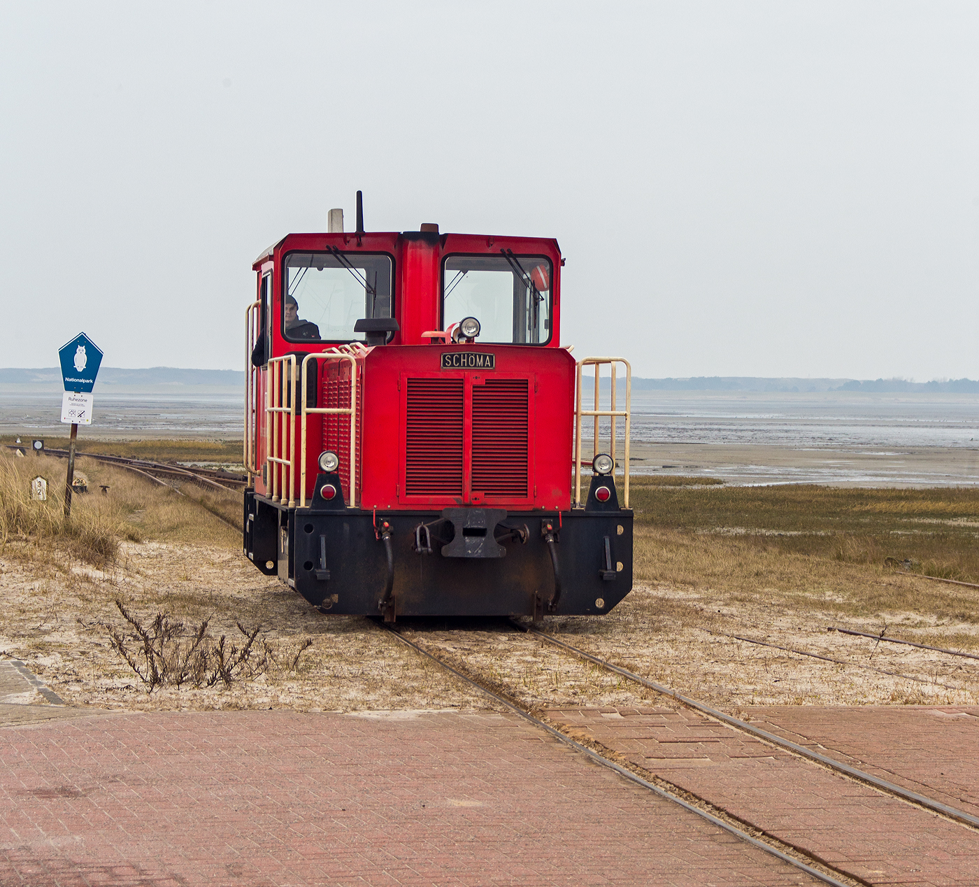 Die DB 399 108-0 (98 80 3399 108-0 D-DB) der Wangerooger Inselbahn rangiert am 12 März 2024 am Westanleger Wangerooge, an den nun leeren Personenzug (5 Wagen sowie zwei Flachwagen für Gepäckcontainern) heran.

Die meterspurige Lok wurde 1999 von SCHÖMA - Christoph Schöttler Maschinenfabrik GmbH in Diepholz unter der Fabriknummer 5600 für die Inselbahn Wangerooge der Deutsche Bahn AG gebaut und geliefert.
