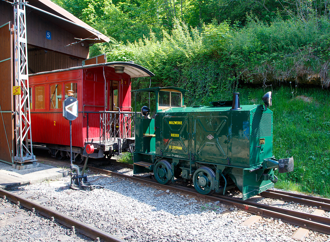 Die doch recht kleine ex MOB Schienentraktor Tm 2/2 Nr. 1, ex Holzwerk Rieder, der Museumsbahn Blonay-Chamby am 27.05.2023 im Museumsareal in Chaulin. 

Die kleine Diesellok, vom Typ O&K RL 2a wurde 1931 von Orenstein & Koppel im Werk Babelsberg unter der Fabriknummer 20200 gebaut und an die Grande Dixence SA für die Baustelle der ersten Dixence-Staumauer  geliefert, wo sie bis 1940 im Einsatz war. Im 1941 wurde sie dann von der Firma Mauerhofer & Zubner, für den Einsatz von Bauzügen beim Fahrleitungsumbau bei der MOB übernommen. 1950 wurde die kleine Lok an das Holzwerk Rieder in St. Stephan verkauft, diese Farbgebung trägt sie auch aktuell bei der BC. Die Lok trägt Fabrikschilder der MBA, wobei die Umbenennung der O&K in Maschinenbau und Bahnbedarf Aktiengesellschaft, vormals Orenstein & Koppel (MBA) erst im Februar 1940 erfolgte.

Die MOB (Montreux-Berner Oberland-Bahn / Montreux Oberland Bernois) kaufte die Lok dann 1979 wieder zurück und bezeichnete sie als Tm 2/2 1. Bei der MOB wurde sie für Rangierarbeiten, von Zementwagen auf Rollböcken in St. Stephan eingesetzt. Die Lok wurde 1995 von der MOB ausrangiert verbleib aber erst noch im Depot Montbovon. 2006 ging sie dann an die Museumsbahn Blonay-Chamby.

Die Lok hat einen 2-Zylinder-Orenstein & Koppel-Dieselmotor mit 22 PS (16 kW) Leistung, die Leistungsübertragung erfolgt über ein Zweigang-Konuskupplungs-Wendegetriebe mit stufenloser Geschwindigkeit Regulierung, über zwei Rollenketten auf die vordere Achse und von dieser über eine Rollenkette auf die hintere Achse. Das Zweigang-Konuskupplungsgetriebe ermöglicht zwei verschiedene Geschwindigkeitsstufen für beide Fahrtrichtungen. Dabei laufen immer beide Gänge im Eingriff, jeweils einer wird eingekuppelt. Eine einfache Wendeschaltung im Getriebe ermöglicht den Fahrtrichtungswechsel bei Stillstand der Lokomotive. Die einfache Bauart des Getriebes hat sich schon bei den Benzinloks bewährt und wurde bei fast allen O&K-Loks der unteren Leistungsklassen angewendet.

TECHNISCHE DATEN:
Spurweite: 1.000 mm (Meterspur)
Achsfolge: B
Länge über Puffer: 4.490 mm
Kastenlänge: 3.450 mm
Höhe: 2.270 mm
Breite: 1.240 mm
Achsabstand: 1.170 mm
Raddurchmesser : 550 mm
Eigengewicht: 7.000 kg
Leistung: 16 kW (22 PS)
Höchstgeschwindigkeit: 7 km/h
Achslager: Gleitlager

Die O&K Typenbezeichnung  RL  stand für  Rohöl  (= Diesel).

Anfang des 20. Jahrhunderts war es noch üblich bei und auf Großbaustellen Feld- oder Schmalspurbahnen zu bauen und zu betreiben. Heute durch Entwicklung von moderner und oft sehr schweren Baumaschinen und Muldenkipper eigentlich undenkbar.