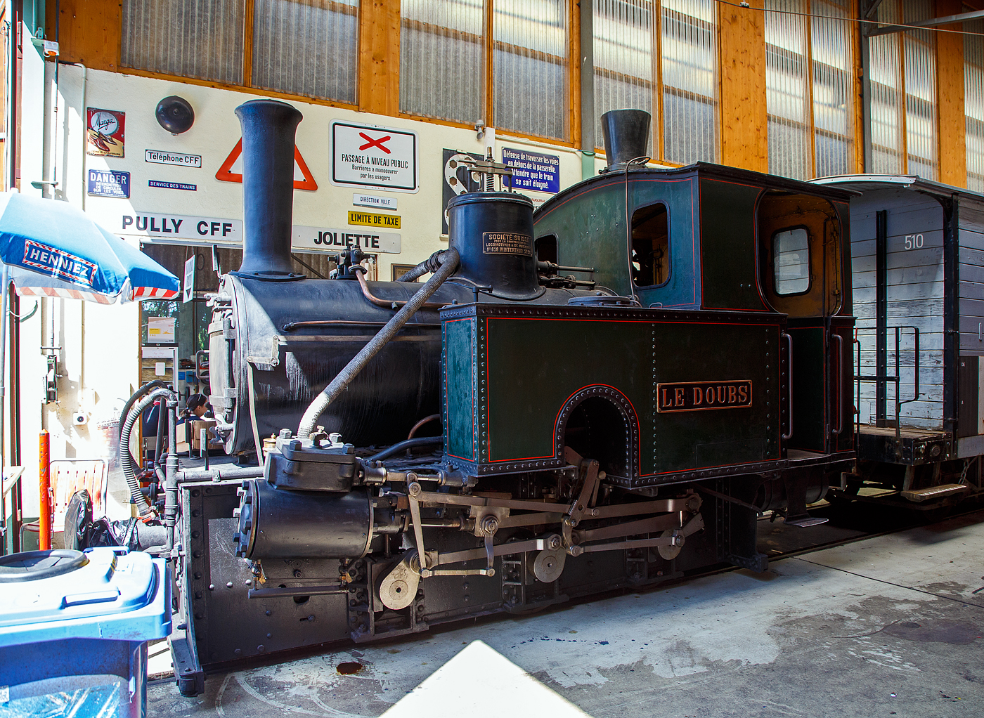 Die ehemalige Dampflokomotive RbB G 3/3 Nr. 1  Le Doubs  der Museumsbahn Blonay-Chamby, hier am 27.05.2023 in der Halle der (BC) in Chaulin.

Die Lok wurde 1890 von SLM (Schweizerische Lokomotiv- und Maschinenfabrik) unter der Fabriknummer 618 gebaut und an die kleine Bahngesellschaft Régional des Brenets geliefert. Am Fabrikschild steht auch der französische Name der SLM „Societe Suisse pour la construction de locomotives et de la Machines“

Das Ende des 19. Jahrhunderts war das goldene Zeitalter der dampfenden Lokalbahnen. So wurde am 1. September 1890 von der Chemin de fer Régional des Brenets (RdB) die meterspurige ca. 4 km lange Bahnstrecke von Le Locle (beginnt neben dem Normalspurigen der SBB) nach Les Brenets eingeweiht, um vor allem Touristen die in die kleine Gemeinde zu bringen. Les Brenets ist ein beliebtes Ausflugsziel dank seiner schönen Lage, dem Lac des Brenets und dem am Doubs unterhalb des Sees liegenden 27 m hohen Wasserfall Saut du Doubs.

Drei kleine Lokomotiven teilen sich den Betrieb, die 1  Le Doubs , 2  Père Frédéric  und 3  Les Brenets. Das weitere Rollmaterial bestand aus 8 Personenwagen und 2 Güterwagen.

Aufgrund der schlechten wirtschaftlichen Lage wurde auf Basis des Privatbahnhilfegesetzes von 1939 die Fusion mit der ebenfalls meterspurigen Ponts–Sagne–Chaux-de-Fonds-Bahn (PSC) in die Wege geleitet, obwohl keine Gleisverbindung zu dieser besteht. Umgesetzt wurde die Fusion 1947, woraus die Chemins de fer des Montagnes Neuchâteloises (CMN) entstand. Unter der CMN wurde die Bahnstrecke Le Locle–Les Brenets modernisiert und der elektrische Betrieb unter 1500 Volt Gleichstrom mit neuem Rollmaterial am 1. Juli 1950 aufgenommen. Seit 1999 wird die isolierte Bahnlinie von der Transports Publics Neuchâtelois (TransN) betrieben.

Nach der Elektrifizierung im Jahr 1950 wurden die Lokomotive 1 sowie die Wagen AB 2 und BD 21 an die SBB zur Aufnahme in die Sammlung des Luzerner Museums gespendet. Da Platz fehlte, wurde das Rollmaterial in Vallorbe abgestellt und 1973 an die Blonay-Chamby ausgeliehen. 1976 gingen die Lokomotive und Wagen in den Besitz der BC über.

Überraschenderweise wurde bei der Elektrifizierung der Strecke 1950 keine Dampflokomotive abgerissen, und alle drei Maschinen haben bis heute überlebt. Die G 3/3 2  Le Père Frédéric  steht als Denkmal überdacht in Les Brenets.

TECHNUISCHE DATEN:
Baujahr: 1890
Hersteller: SLM (Fabrik-Nr. 618)
Spurweite: 1.000 mm
Achsformel: C
Länge über Puffer: 5.210mm
Achsabstand: 1.800 mm (2 x 900mm)
Dienstgewicht: 16 t
Anzahl der Zylinder: 2
Zylindergröße: Ø 240 mm x 350 mm Kolbenhub
Treibraddurchmesser: 750 mm
Höchstgeschwindigkeit: 25 km/h
Kesselüberdruck: 12 bar
Kohlevorrat: 0,5 t
Wasservorrat: 1,8 m³