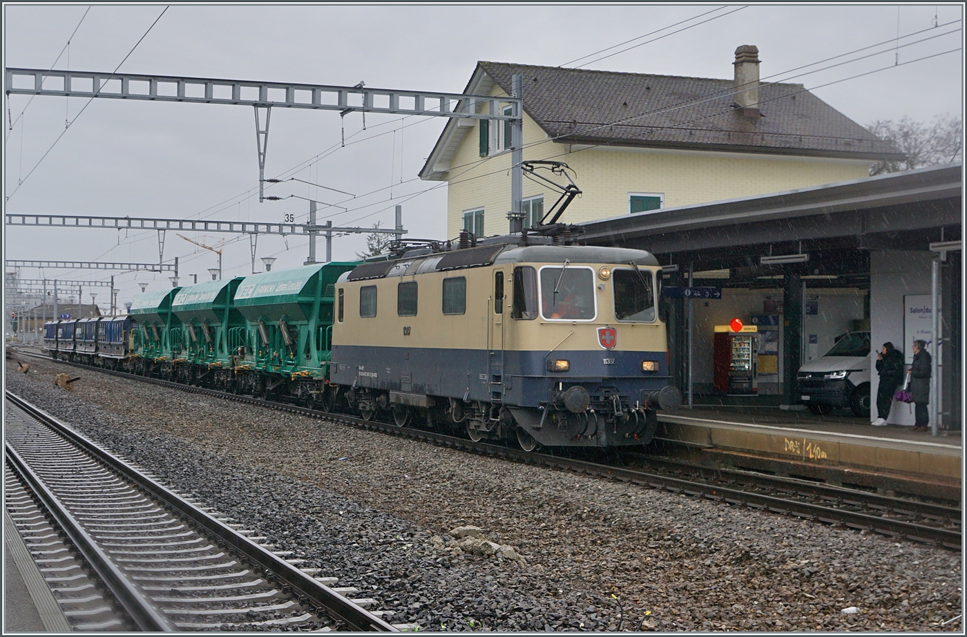Die IRSI Re 4/4 II 11387 (Re 421 387-2) hat mit ihrem Kieszug das Kieswerk verlassen und ist nun auf Gleis 1 in Gland für die Rückfahrt nach Morges bereit. 

22. Feb. 2024