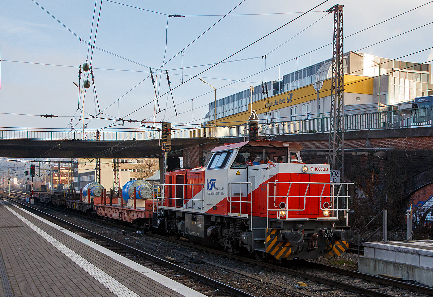 Die KSW 47 (92 80 1271 027-5 D-KSW), ex D 2 der HFM, eine Vossloh G 1000 BB der KSW (Kreisbahn Siegen-Wittgenstein), fährt am 15.12.2022 von Siegen-Ost kommend mit einem Walzenzug (Schwerlastwagen beladen mit gegossenen Walzen) durch den Hauptbahnhof Siegen in Richtung Siegen-Eintracht (zur KSW Zentrale).

Nochmals einen lieben Gruß ans nette KSW Personal zurück.