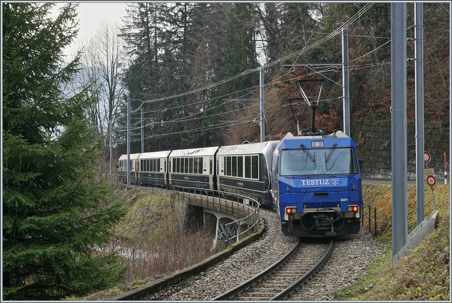 Die MOB Ge 4/4 8001 ist als Schublok mit dem GoldenPass Express 4065 von Interlaken nach Montreux unterwegs. Die Ge 4/4 8001 hat den Zug in Zweisimmen übernommen und rollt nun kurz nach der 93 Meter langen Pont Gardiol, welche den Bois des Chenaux überbrückt, ihrem Ziel Montreux entgegen.

4. Januar 2023