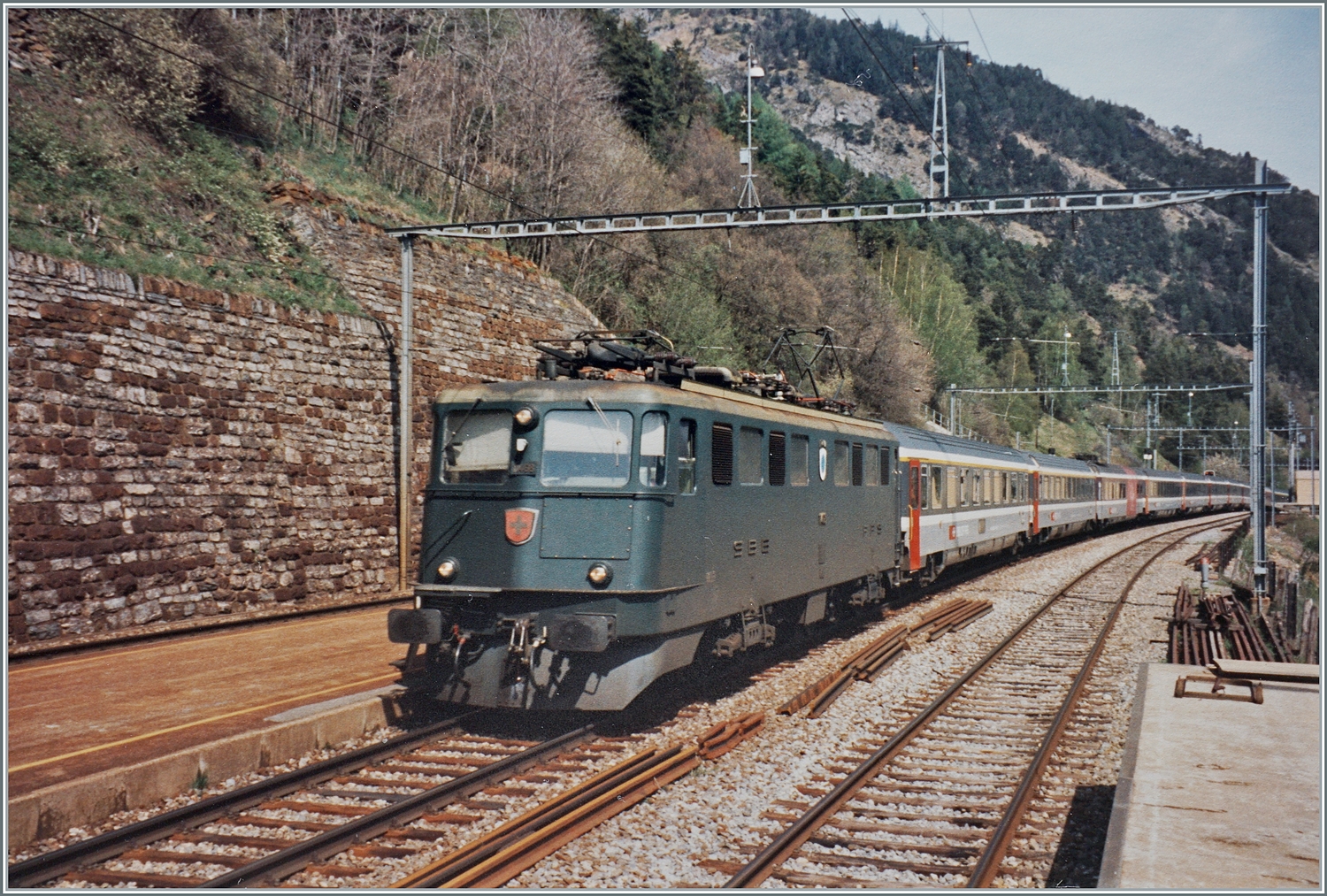 Die SBB Ae 6/6 11468  Lenzburg  ist im Frühsommer mit dem EC  Matterhorn  von Brig nach Wiesbaden auf der BLS Südrampe bei Hohtenn unterwegs.

Analogbild vom Mai 1995