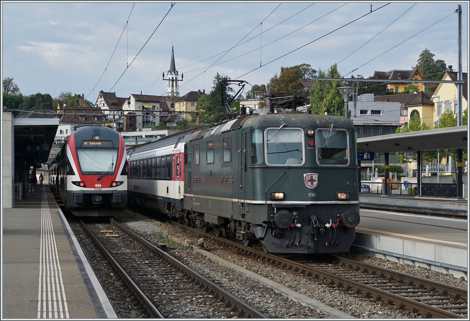 Die SBB Re 4/4 II wartet mit ihrem IC 4 nach Singen in Schaffhausen auf die baldige Weiterfahrt, während der SBB RABe 511 023 als RE nach Zürich fahren wird.

9. Sept. 2022