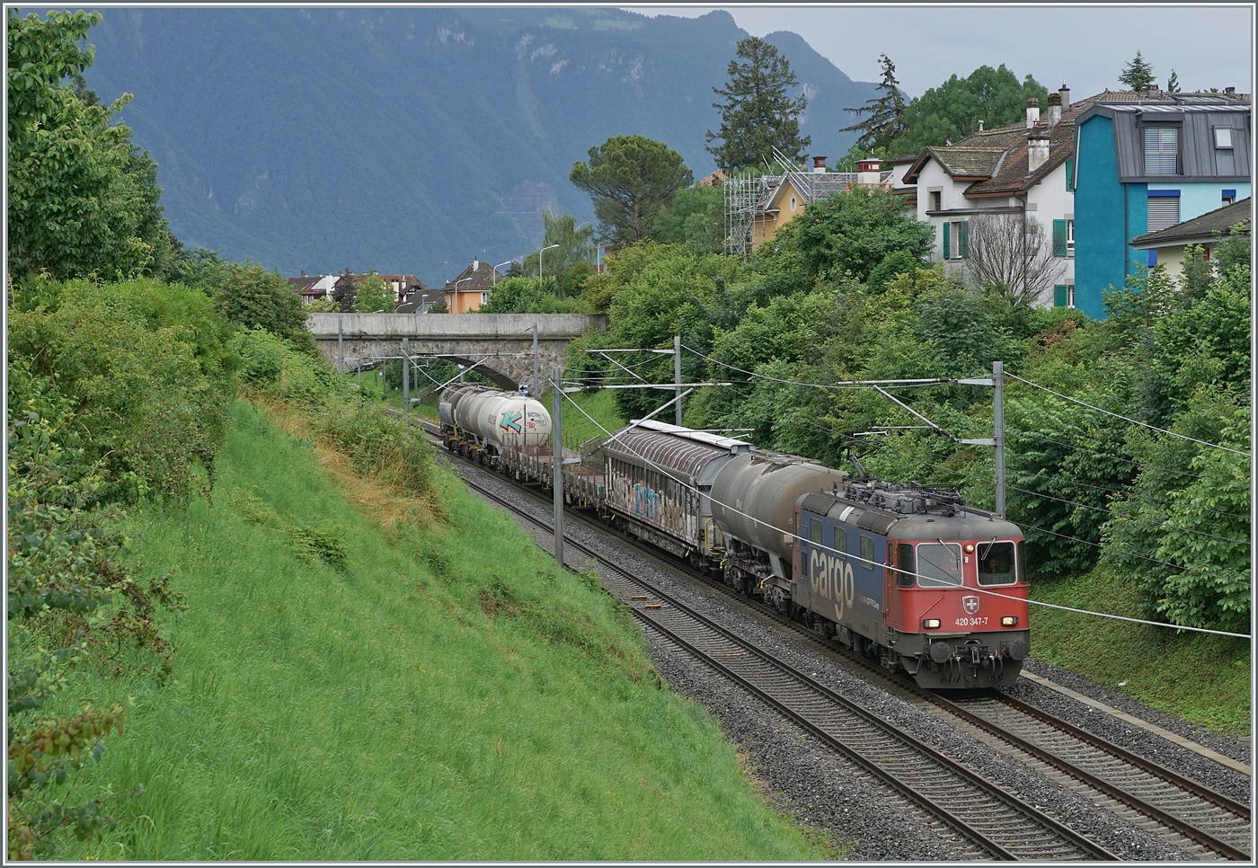 Die SBB Re 4/4 II 11347 (Re 420 347-7) ist mit einem Güterzug bei La Tour-de-Peilz auf dem Weg in Richtung Lausanne. 

21. Juni 2024