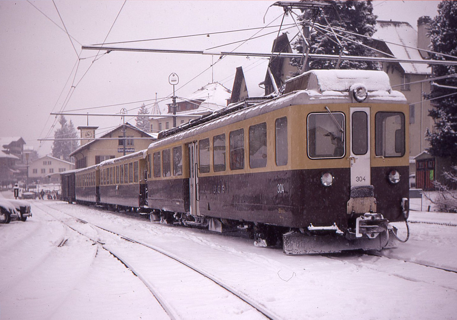 Die Triebwagen der Berner Oberland Bahn BOB ABeh4/4 I 304-310: Nachdem bis 1965 alle 9 kleinen Lokomotiven im Einsatz standen und die Fahrt besonders nach Grindelwald qu�lend langsam voranging (manchmal mit erheblichem Fluchen der ungeduldigen Passagiere) konnten jetzt 5 neue Triebwagen ABeh4/4 I die 3 �lteren Triebwagen von 1948 endlich erg�nzen. Im Bild steht eine sehr klassische Komposition ohne Einheitswagen in Grindelwald, Triebwagen 304. 30.Dezember 1970. 