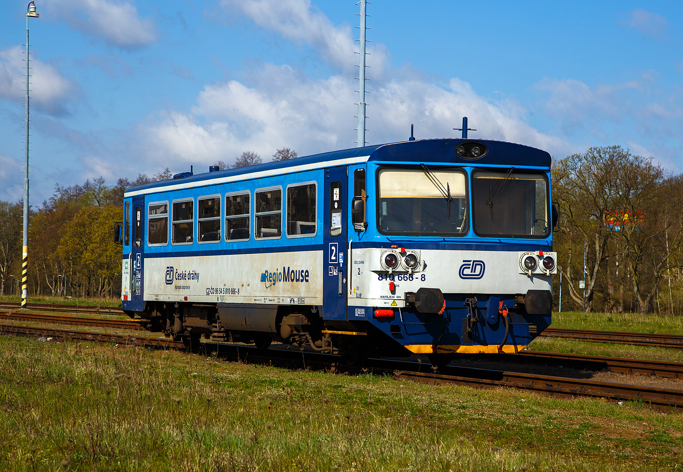 Die zur „RegioMouse“ modernisierte “Chcpk”  (Brotbchse) bzw. der zweiachsige Dieseltriebwagen ČD 810 666-8 (CZ-ČD 95 54 5 810 666-8), ex ČSD M 152.0566, ist am 19.04.2023 beim Bahnhof Karlovy Vary doln ndra (Karlsbad unterer Bahnhof) abgestellt.

Der Dieseltriebwagen wurde 1982 von Vagnka Studnka unter der Fabriknummer  87866  fr die damalige ČSD Československ sttn drhy (Tschechoslowakischen Staatsbahnen als ČSD M 152.0666 gebaut.

Die zweiachsige Dieseltriebwagen fr den Regionalverkehr wurden als Baureihen M 152.0 (ab 1988: Baureihe 810) fr die Tschechoslowakischen Staatsbahnen (ČSD) gebaut. Die Fahrzeuge bilden die dritte Generation zweiachsiger Triebwagen der ČSD. Die seit 2018 einer zweiten Modernisierung unterzogenen Fahrzeuge der ČD-Baureihen 809 und 810 werden als „RegioMouse“ vermarktet.

Ab 1975 wurden bei Vagonka Tatra in Studnka (heute koda Vagonka a.s.) in sieben Bauserien 680 zweiachsige Dieseltriebwagen fr die ČSD als Baureihe M 152.0 gebaut. Nahezu baugleiche Fahrzeuge wurden an die Ungarischen Staatsbahnen (MV), als Bzmot, geliefert. Passend zu den Triebwagen wurden entsprechende Beiwagen vom Typ Blm geliefert, welche in Aufbau und Aussehen identisch mit den Triebwagen sind. Jedem Triebwagen konnten zwei Beiwagen beigegeben werden. Aufgrund der eckigen Aufbauten erhielten die Triebwagen von deutschen Eisenbahnfreunden den Spitznamen „Brotbchse“.

Zwischen 1987 und 1990 fhrten die ČSD EDV-gerechte Triebfahrzeugnummern ein. In der bergangszeit wurden die EDV-Nummern zustzlich zu den alten Gussschildern mit Klebeziffern angebracht. Die Triebwagen erhielten die Reihenbezeichnung 810, die Beiwagen 010. Beide Nachfolgeunternehmen der ČSD behielten den Nummernplan bei, allerdings wurden freizgig einsetzbare Beiwagen 2009 auch nummernmig in den Reisezugwagenpark aufgenommen.

Nach der Teilung der Tschechoslowakei in die Nachfolgestaaten Tschechien und Slowakei am 1. Januar 1993 wurden Trieb- und Beiwagen auf die neugegrndeten Staatsbahnen ČD und SR aufgeteilt. In der Slowakei gehren die Fahrzeuge heute zum Bestand des Nachfolgeunternehmens elezničn spoločnosť Slovensko (ZSSK).

Technische Merkmale:
Die Triebwagen haben keine Vielfachsteuerung, passende Steuerwagen existieren nicht. Deshalb muss bei mehrteiligen Einheiten jeder Triebwagen mit einem Triebfahrzeugfhrer besetzt sein. Die Triebwagen mssen, wenn sie mit entsprechenden Beiwagen verkehren,  an Endbahnhfen stets an die jeweilige Zugspitze umgesetzt werden.

Aufbau des Triebwagens:
Der Triebwagen ist eine Leichtbaukonstruktion. Der Wagenkasten besteht aus gewalzten und abgekanteten Stahlprofilen, die mit Stahlblech verkleidet sind. Innen ist das Gerippe mit Spanplatten, die mit Sprelacart berzogen sind, verkleidet. Der Fuboden besteht aus wasserbestndigem Sperrholz von 15 Millimetern Dicke und ist mit einer zwei Millimeter starken Schicht aus PVC beklebt. An jedem Ende des Wagenkastens befindet sich ein vom Fhrerstand abgetrennter Einstiegsraum, der auf beiden Seiten jeweils eine vom Fhrerstand schliebare pneumatische Schiebetr besitzt.

Das Fahrgastabteil besitzt 56 Sitzpltze in der Anordnung 3+2 mit Mittelgang, die ursprnglich schaumgummigepolstert waren. Zustzlich bietet ein Wagen etwa 40 Stehpltze. Der Fahrgastraum hat auf jeder Seite sechs Fenster mit der lichten Weite von 1316  841 mm, deren oberer Teil klappbar ist. Groe Frontscheiben mit Scheibenheizung, Scheibenwischern und Sonnenschutzblende ermglichen eine gute Streckenbeobachtung. Durch die Anordnung einer zustzlichen Trennwand fielen die Fhrerstnde sehr kurz aus. Um eine befriedigende Sitzposition fr den Triebwagenfhrer zu ermglichen, musste die Trennwand im Bereich seines Sitzes ausgeschnitten werden. Der Ausschnitt ist mit einer in den Einstiegsraum reichenden Blechabdeckung verschlossen.

Die Beiwagen entsprechen im Aufbau den Triebwagen, abgesehen von der fehlenden Antriebsanlage. An Stelle der Fhrerstnde ist an den Wagenenden eine durchgehende Sitzbank vorhanden.

Laufwerk und Antriebsanlage:
Gefhrt wird das Fahrzeug von zwei einachsigen Drehgestellen, von denen eines ber eine Gelenkwelle angetrieben wird. Damit sind beide Radstze im Bogen radial einstellbar. Die Drehgestelle sttzen sich mit Schraubenfeder auf den Achslagern ab. Die Aufhngungen sind mit dem Wagenkasten ber Gummiblcke verbunden. Auf der Treibachse, die beidseitig gesandet werden kann, sitzt das Wendegetriebe zur Umsteuerung der Fahrtrichtung. Bei den Triebwagen sind beide Radstze mit einer Spurkranzschmiereinrichtung ausgerstet.

Als Antriebsanlage ist ein nicht aufgeladener Dieselmotor vom Typ LIAZ ML 634 unterflur eingebaut. Dieser besitzt sechs Zylinder in Reihe mit Direkteinspritzung und ist mit dem Getriebe vom Typ Praga 2M 70 direkt verbunden. Die gesamte Antriebsanlage besteht bis auf das Achswendegetriebe aus Komponenten, die vom Omnibus Karosa M 11 bernommen wurden. 

Die Antriebsanlage und die Hilfseinrichtungen wie Wasserkhlung, lwrmetauscher, Batterie, Kraftstoffbehlter und Warmwasserheizung sind unterflur angeordnet. Deshalb drfen die Triebwagen Ablaufberge nicht befahren. Die Hilfsmaschinen, ein Wechselstromgenerator und ein Kompressor fr die Druckluft der pneumatischen Bremse, werden ber Gelenkwelle und Keilriemen vom Dieselmotor angetrieben. Der Dieselmotor ist wassergekhlt, zustzlich ist ein Lfter mit hydrostatischem Antrieb vorhanden. Dieser wird in Abhngigkeit von der Motordrehzahl und der Khlwassertemperatur automatisch geregelt.

brige Einrichtungen:
Die Triebwagen sind mit indirekter Bremse und direkter Bremse nach dem System DAKO ausgerstet. Gesteuert wird diese mit dem Fhrerbremsventil koda N – 0. Auerdem ist eine Handbremse, die in beiden Fhrerstnden bedient werden kann, vorhanden. In beiden Einstiegsrumen und dem Fahrgastraum befinden sich Notbremshhne.

Beheizt wird das Fahrgastabteil des Triebwagens durch Warmluft. Hierzu wird das Khlwasser aus dem Motorkreislauf einem Wrmetauscher zugefhrt, der unter den Sitzen angebracht ist. Bei nichtarbeitendem Dieselmotor wird ein Vorwrmgert verwendet. Der Fhrerstand wird mit einer Warmwasserheizung beheizt. Die Beiwagen werden elektrisch beheizt. Belftet wird das Abteil der Reisenden ber Dachlfter. Die Beleuchtung des Fahrgastabteiles bernimmt der Wechselstromgenerator. Durch die Ausrstung der Trieb- und Beiwagen mit Seitenpuffern und Schraubenkupplung ist es mglich, die Fahrzeuge mit anderen Fahrzeugen zu kuppeln. Daher knnen die Triebwagen vereinzelte Gtertransporte auf Nebenbahnen durchfhren. Die Schraubenkupplungen entsprechen der bei Dieseltriebwagen der ČSD blichen leichten Ausfhrung, die damit ausgersteten Wagen drfen in Regelzgen nur am Schluss eingestellt werden.

Umbauten in Tschechien  (der ČD): 
1994 begann der Umbau von 28 Einheiten fr den schaffnerlosen Betrieb. Dabei wurde die Inneneinrichtung gendert. 1996 wurden diese Einheiten in die ČD-Baureihe 809 umgezeichnet.

Von 2005 bis 2012 wurden die Fahrzeuge der ČD durch die Firma Pars Nova (gehrt zu koda) grundlegend modernisiert und umgebaut. Dabei entstanden zweiteilige Einheiten, die jeweils aus einem Triebwagen und einem teilweise niederflurigen Steuerwagen bestehen. Ein Teil der Triebzge wurde als dreiteilige Einheit mit zwei Triebwagen und einem dazwischen eingestellten Beiwagen zusammengestellt. Bei den Wagen, die einen zwischen den Radstzen abgesenkten Wagenboden erhielten, wurden die Einstiege von den Enden in Wagenmitte verlegt.

Im Februar 2018 wurde als letzte Modernisierung die Baureihe 816 von GW Train Regio vorgestellt.

Einsatz:
Die Fahrzeuge besitzen eine Zulassung fr den Verkehr nach Deutschland und sterreich. Im grenzberschreitenden Nahverkehr gehrten sie auf den Grenzbahnhfen Zittau, Ebersbach (Sachs), Bad Schandau, Johanngeorgenstadt, Furth im Wald und Bayerisch Eisenstein zum tglichen Bild. 

Trotz des Umbauprogrammes existieren nach wie vor einige Fahrzeuge, die sich bis auf eine Teilmodernisierung des Fahrgastraumes mit neuer Bestuhlung noch weitgehend im Originalzustand befinden. Sie kommen weiterhin auf Strecken mit geringem Verkehrsaufkommen planmig zum Einsatz. Bei den ČSD war es blich, Beiwagen von Verbrennungsmotortriebwagen auch als lokbespannte Reisezge einzusetzen. Die Nachfolger behielten diese Betriebsweise bei.

TECHNISCHE DATEN :
Hersteller: ČKD Vagnka in Studnka (heute koda Vagonka a.s.)
Spurweite: 1.435 mm (Normalspur)
Achsformel: 1'A' 
Lnge ber Puffer: 13.970 mm
Hhe: 3.500 mm
Achsabstand: 8.000 mm
Dienstgewicht: 20 t
Radsatzfahrmasse: 10 t
Hchstgeschwindigkeit: 80 km/h
Installierte Leistung: 155 kW (bei 1.950 U/min)
Anfahrzugkraft: 29 kN 
Motorbauart: Sechszylinder-Reihendieselunterflurmotor
Motorentyp: LIAZ ML 634
Motorhubraum: 11,946 Liter (Zylinder- 130 mm / Kolbenhub 150 mm)
Nenndrehzahl: 2.150 U/min (Leerlaufdrehzahl 600 U/min)
Kompressionsverhltnis: 12,5 : 1
Getriebe: Praga 2M70
Leistungsbertragung: hydromechanisch
Sitzpltze: 55
Tankinhalt: 300 l
Fubodenhhe: 570 mm (Niederflurteil)
Kleinster befahrbarer Gleisbogen: R 100 m

Quellen: Wikipedia, atlaslokomotiv.net