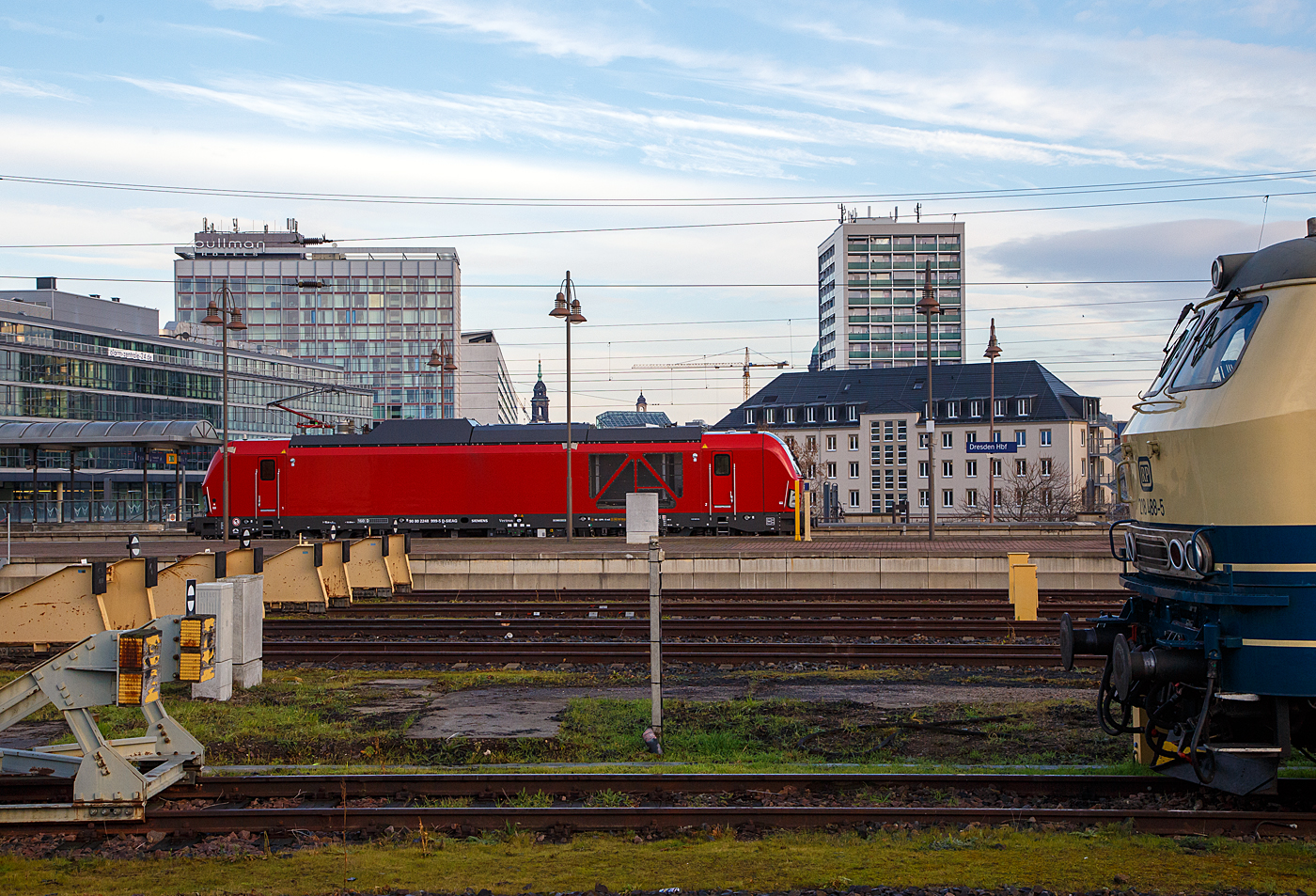 Diese Lokomotivbaureihe wird man bald auf deutschen Gleisen wohl öfters sehen können. Denn die DB Cargo erneuert seine Rangier- und Strecken-Lokflotte und beschafft neue Zweikraftlokomotiven der BR 248, als Ersatz für die älteren Diesellokomotiven der Reihe 294 (V 90). Es wurde Rahmenvertrag mit dem Hersteller Siemens Mobility über bis zu 400 Fahrzeuge, die einem Investitionsvolumen von deutlich über einer Milliarde Euro entsprechen, angeschlossen. Geliefert werden Lokomotiven vom Typ Vectron Dual Mode mit spezifischen Anpassungen für das von DB Cargo geplante Einsatzspektrum. Zunächst bestellt die DB Cargo 100 Loks der Baureihe 248. Die Auslieferung startet ab 2023. Die DB Loks sind aber stark modifiziert, so soll bei ihnen die Achslast maximal 21 t betragen (statt 22,5 t). Sie erhalten in den Führerständen einen zusätzlichen Seitenfahrschalter und einem Mikrofon statt des gewohnten Seitenfensters versehen. 

Hier fährt am 08.12.2022, die sehr neue (Baujahr 2022) Siemens Vectron Dual Mode 248 999-5 (90 80 2248 999-5 D-SIEAG) der Siemens Mobility GmbH (evtl. Vorführmaschine) durch den Hauptbahnhof Dresden in westlicher Richtung.

Die Vectron DM wurden 2022 von Siemens Mobility GmbH in München-Allach unter der Fabriknummer 23166 gebaut.

Der Vectron Dual Mode vereint die Vorteile einer vollwertigen Diesellokomotive mit denen von elektrischen Lokomotiven. Dank des leistungsstarken Dieselantriebs sowie der Ausstattung für die Nutzung der Fahrleitung kann man jederzeit flexibel auf die Traktionsanforderungen reagieren. So bleibt man immer in Bewegung, egal ob mit oder ohne Fahrdraht. Wo ein Fahrdraht ist, sollte man ihn nutzen. Denn der Betrieb unter Oberleitung ist im Vergleich zum Dieselbetrieb deutlich kosteneffizienter und umweltfreundlicher. Doch weil es in Deutschland noch lange Zeit Strecken geben wird, die nicht vollständig elektrifiziert sind, fahren viele Diesellokomotiven unter Fahrdraht weiter. Das ist aber ökonomisch und ökologisch wenig sinnvoll. Dies ist hier ein Beispiel einer echten Alternative. 

Mit der Vectron Dual Mode ist es möglich Güterzüge aus dem Umland umweltschonend in die Zentren der Ballungsräume zu befördern. Nur so einfach, wie in der Siemens Werbung ist es auch nicht, denn die Lok vier Achsen (Bo’Bo’) und wiegt 90 t, so ergibt sich eine Achslast  von 22,5 t. Nicht elektrifizierte Nebenstrecken haben nicht gerade alle von min. D2 (22,5 t), und können so auch nicht befahren werden. Auch die Leistung der DM im Vergleich zu heutigen Hochleistungselektrolokomotiven ist mit 2.400 kW erheblich geringer. Mit den Dieselstreckenloks kann sie aber mit 2.000 kW sehr gut mithalten, zudem liegt die Anfahrzugskraft bei stattlichen 300 kN.

TECHNISCHE DATEN der Siemens Vectron Dual Mode (BR 248)
Spurweite: 1.435 mm
Achsformel: Bo'Bo'
Länge über Puffer: 19.975 mm
Drehzapfenabstand: 10.800 mm
Achsabstand im Drehgestell: 2.700 mm
Breite: 3.020mm
Höhe:  4.220 mm
Raddurchmesser :  1.100 mm (neu) / 1.020 mm (abgenutzt)
Gewicht:  90 t (bei vollen Vorräten)
Achslast: 22,5 t
Spannungssysteme (bei E-Betrieb): 15 kV, 16,7 Hz
Dieselmotor: MTU 16V 4000 R84 (16-Zylinder-V-Motor)
Dieselmotorleistung an der Kurbelwelle: 2.400 kW
Max. Leistung am Rad: 2.400 kW bei E-Antrieb / 2.000 kW bei D-Antrieb
Höchstgeschwindigkeit:160 km/h
Antriebsart: elektrisch oder dieselelektrisch
Kraftübertragung :Teilabgefederter Antrieb (Ritzelhohlwellenantrieb)
Kraftstoffbehälter Nutzvolumen: 2.600 l
Anfahrzugskraft:  300 kN
Elektrische Bremskraft: 150 kN
Elektrische Bremsleistung (am Rad): E-Betrieb 2.100 kW / Dieselbetrieb 1.700 kW
Doppeltraktion: Über WTB ÖBB mit typgleichen Fahrzeugen sowie Vectron E, Vectron DE und ER20
Zugsicherung: PZB / für ETCS vorbereitet
