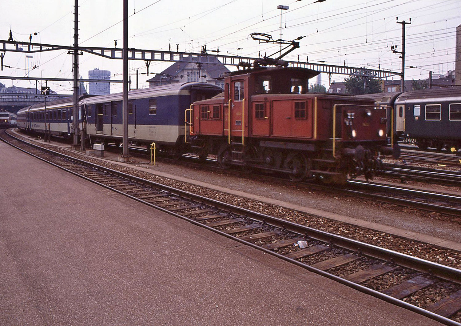 Ee 932 (Ee 3/3 II): Die Zweisystemlok (Wechselstrom SNCF 25 kV 50 Hz / SBB 15 kV 16,7 Hz) 16513  zieht einen schweizer Schnellzug in Basel SBB vor in Richtung der SNCF Strecke. Der erste Wagen ist ein weiss/blauer Gepckwagen, der noch als BN beschriftet ist (Bern - Neuchtel). 22.Juni 1989.   