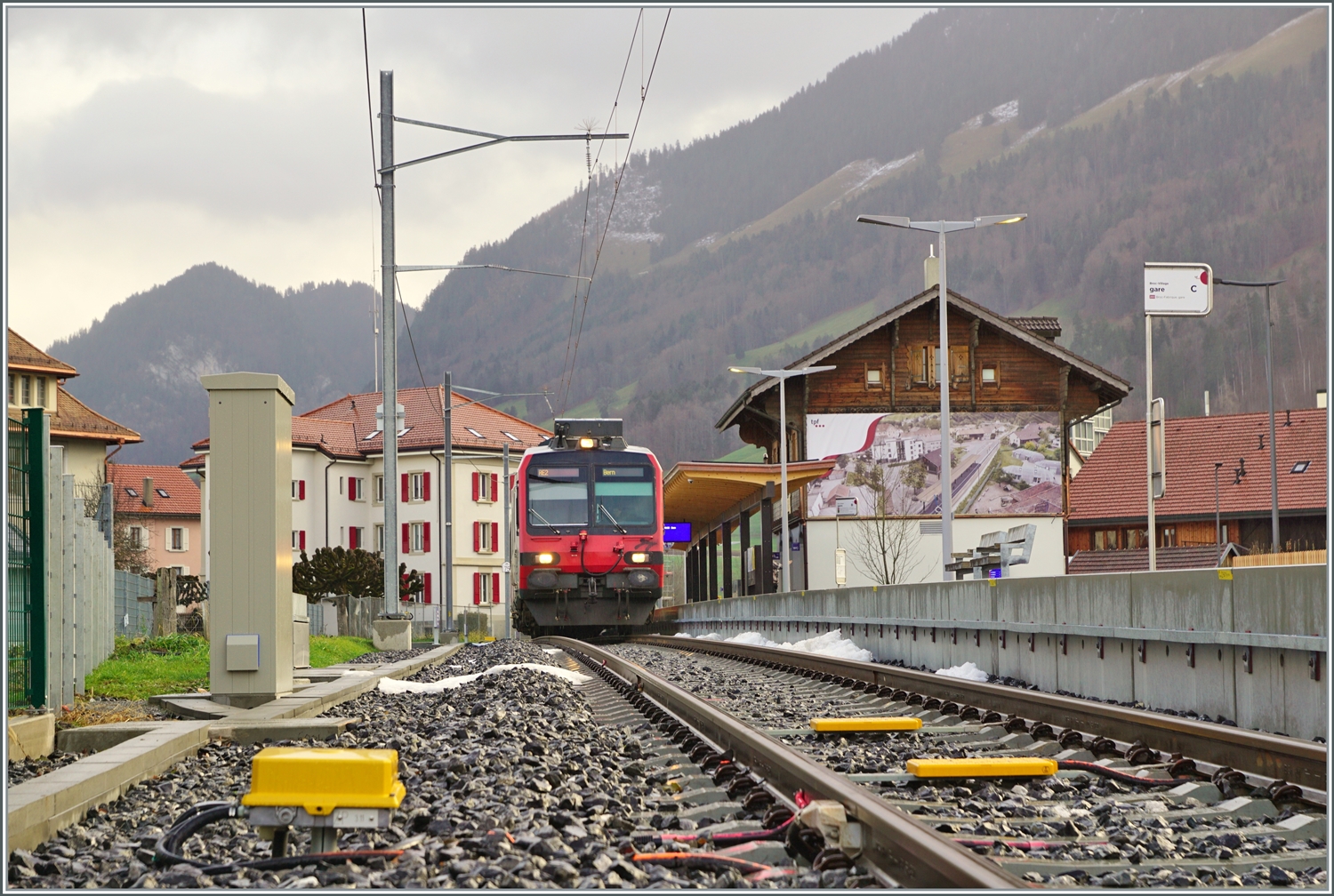 Ein Bild, welches nur eine relativ kurze Zeit gemacht werden kann: Während der SBB RBDe 560 Domino in Broc Villages wendet, kann vom geöffneten Bahnübergang der Zug und die näher Umgebung des Bahnhofs von Broc Village fotografiert werden. Wird der Zug ab August von Bulle Fabrique kommen, dürfte bei der Ankunft des Zuges die Barriere bereits geschlossen sein.

22. Dezember 2022