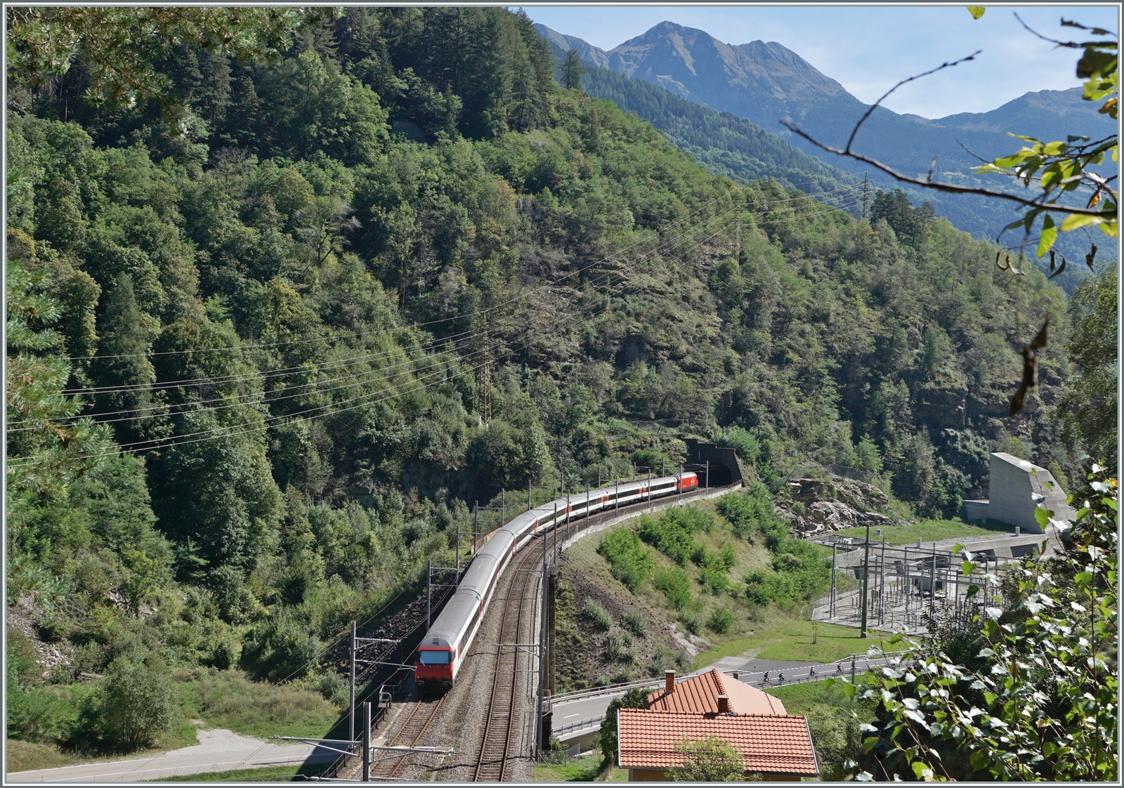 Ein SBB IC 2 nach Lugano auf der103 Meter langen Polmengobrücke über den  Tessin . Ganz rechts im Bild der Eingang zur  Multifunktonsstation  Faido  des GBT. 

4. Sept. 2023