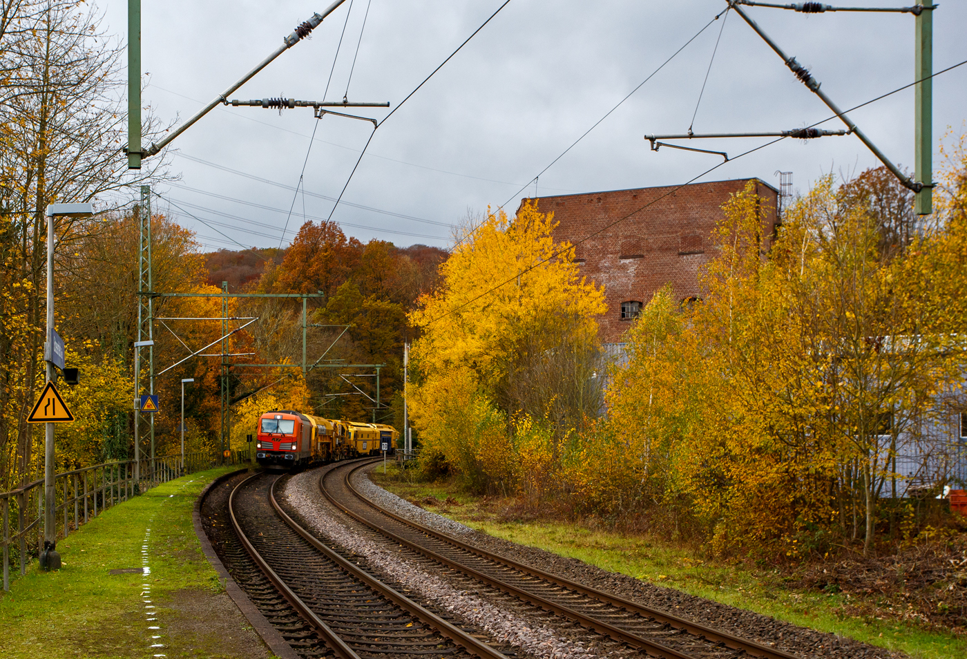 Es ist wie es ist, manchmal ist man einfach auf der falschen Gleisseite. Die 247 902 (92 80 1247 902-0 D-RTS) der RTS Rail Transport Service GmbH, Graz (eine 100%ige Tochter der Swietelsky Baugesellschaft m.b.H) fährt am 03 November 2025 mit einem P&T Schotterbewirtschaftungssystem BDS 2000-4 (eine Schotterverteilmaschine), sowie einer P&T UNIMAT 09-32/4S Dynamik (eine Universalstopfmaschine mit dynamischem Gleisstabilisator) am Haken durch Scheuerfeld/Sieg in Richtung Siegen. Beide Plasser & Theurer Maschinen gehören der Swietelsky Baugesellschaft m.b.H, wobei die BDS 2000-4 wohl in Österreich und die UNIMAT 09-32/4S in Deutschland eingesellt sind. 

Nochmals einen lieben Gruß an den netten Lokführer zurück.

Die Siemens Vectron DE wurde 2015 von Siemens Mobility GmbH in München-Allach unter der Fabriknummer 21762 als Vorführlok gebaut und eingestellt vom Siemens Prüfcenter Wegberg-Wildenrath als (92 80 1247 902-0 D-PCW). Für Testfahrten war sie bei einigen Bahnen. Ab 2017 war sie für die DB Cargo Deutschland AG (92 80 1247 902-0 D-DB) unterwegs, bis sie 2019 an die RTS - Rail Transport Service GmbH verkauft wurde. Zugelassen ist die Dieselelektrische Lok in Deutschland und Österreich, mit einer Höchstgeschwindigkeit von 160 km/h.
