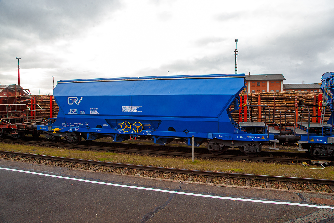 Gedeckter vierachsiger Drehgestell-78m³-Schüttgutwagen mit Schwenkdach und schlagartiger mittigen Schwerkraftentladung (Mittenselbstentladewagen) 33 80 0689 096-0 D-ORWU, der Gattung Tanoos, der Waggonvermietungsfirma On Rail GmbH (Mettman), abgestellt am 24.11.2022 im Bahnhof Schwandorf.

Der Wagen ist für den Transport von nässeempfindlichen Schüttgütern insbesonders korrosiv wirkenden, wie Kali sowie andere Düngemittel und Salze in granulierter Form, geeignet. Aus diesem Grund sind besonders gefährdete Bauteile und Berührungsstellen aus korrosionsfestem Stahl gefertigt. Der Wagenkasten besteht aus einem trichterförmigen Behälter, ist durchgängig und nur zwischen den Auslauföffnungen unterteilt. Die Entladung erfolgt über pyramidenförmige Auslauftrichter, die vier mittig angeordneten Entladeschieber werden paarweise über je ein Handrad betätigt. Alle Ecken und Aussteifungen sind durch Ausrundungen so gestaltet, dass sich nahezu keine Ladegutreste festsetzen können. Schräggestellte Behälterwände haben eine Neigung von 55° bzw. 60° zur Horizontalen. Der Wagenkasten ist so gestaltet, dass er von außen maschinell gereinigt werden kann. Die zweischalige Konzeption des manuell bedienbaren Dachs ist mit einer Kippeinrichtung versehen, die eine optimale Innenreinigung ermöglicht.

TECHNISCHE DATEN:
Hersteller: ELH Waggonbau Niesky GmbH
Spurweite: 1.435 mm
Länge über Puffer : 15.800 mm
Drehzapfenabstand: 10.760 mm
Achsabstand im Drehgestell: 1.800 mm
Laufraddurchmesser: 920 mm (neu)
Eigengewicht: 22.800 kg
Höchstgeschwindigkeit:  100  km/h (beladen) / 120 km/h (leer)
Maximales Ladegewicht: 67,2 t (Streckenklasse D oder höher)
Nat. max. Ladegewicht auch: 61, 2 t (DB Streckenklasse CM - 21 t Radsatzlast)
Kleinster bef. Gleisbogenradius: 75 m
Rauminhalt: 78 m³
Bremse: KE-GP-A (K)
Bremssohle: S517 / C 810
Intern. Verwendungsfähigkeit: TEN-GE

Die Bedeutung der Gattungs- und Kennbuchstaben (hier Tanoos):
T - Wagen mit öffnungsfähigem Dach 
a - mit vier Radsätzen
n - mit vier Radsätzen höchste Lastgrenze über 60 t
oo - mit Schwerkraftentladung, schlagartig, mittig, tiefliegend
s - Höchstgeschwindigkeit 100 km/h (beladen)