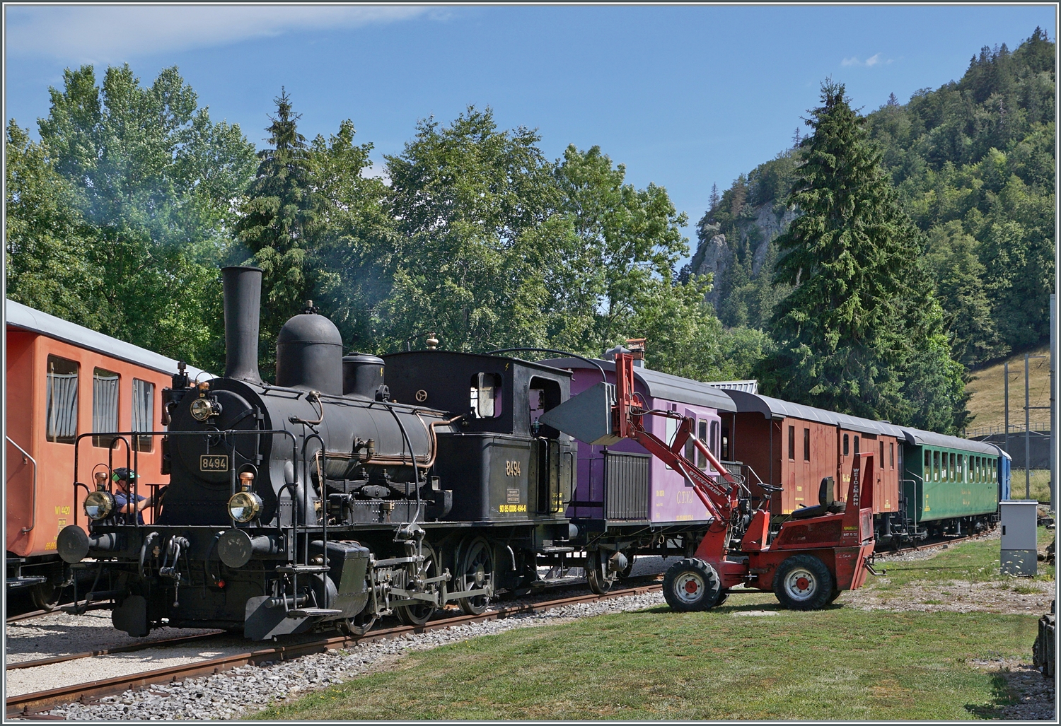 Gut 30 Km weiter ist ein weiteres  Tigerli  am dampfen! Die CTVJ (Compagnie du Train a vapeur de la Vallée de Joux) E 3/3 8494 (UIC 90 85 0008 494-6) mit der SLM Fabriknummer 1974 mit dem Baujahr von 1909 wird im Gelände der CTVJ in Le Pont für den nachmittäglichen Sonderzug nach Le Brassus vorbereitet. Auch hier wird die Lok mit Holz beheizt, welches aus dem (leicht das Bild störenden) Fahrzeug recht des Lok Stück um Stück entnommen wird. 

23. Juli 2023