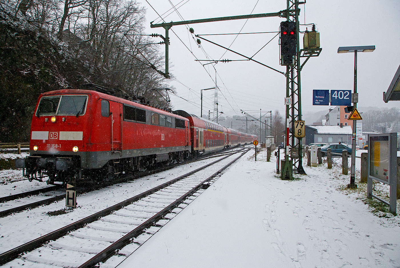 Heute hat es etwas geschneit und es schneit noch.... 
Die 111 168-1 (91 80 6111 168-1 D-DB) der DB Regio NRW rauscht am 19.01.2023 mit dem RE 9 rsx - Rhein-Sieg-Express (Aachen – Köln – Siegen), etwas verspätet durch den Bahnhof Scheuerfeld (Sieg) in Richtung Betzdorf.

Die Lok wurde 1980 von Henschel & Sohn in Kassel unter der Fabriknummer 32441 gebaut. Aktuell wird sie DB Gebrauchtzug am Markt zum Kauf angeboten.