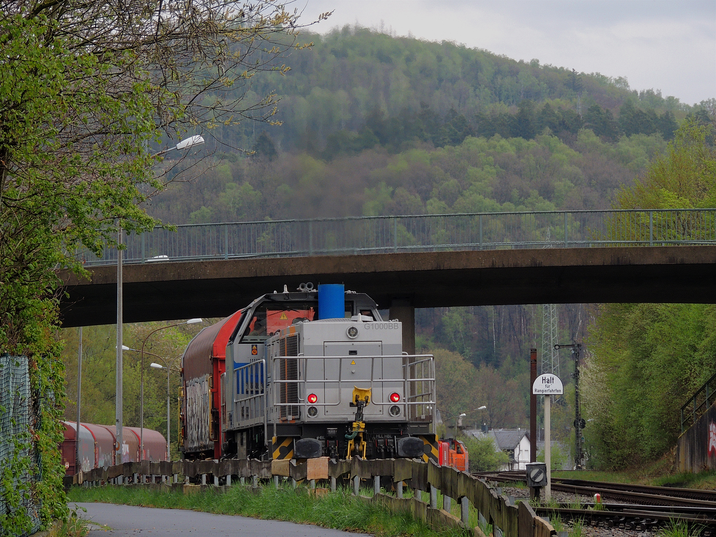 Hochbetrieb in Herdorf am 23 April 2025: 
Durch die vergangenen Osterfeiertage braucht es wohl wieder Nachschub. Die KSW (Kreisbahn Siegen-Wittgenstein) kommt im Sandwich mit einem sehr langen und somit schweren Coilzug, von via Betzdorf/Sieg kommend, und erreicht den KSW-Rangierbahnhof (Betriebsstätte FGE - Freien Grunder Eisenbahn).

Hier am Zugschluss die nachschiebende KSW 47 (92 80 1271 027-5 D-KSW), ex D 2 der HFM, eine Vossloh G 1000 BB, vorne als Zuglok die KSW 44 (92 80 1271 004-4 D-KSW) auch eine MaK G 1000 BB. Im Rbf wird der Zug geteilt, da er für die Weiterfahrt sonst zu lang wäre, und die KSW 44 zieht den ersten Teil weiter zu den Schäfer Werke KG am Pfannenberg in Neunkirchen-Salchendorf. 

Die KSW-Bahnstrecke Herdorf–Pfannenberg-(ehem. Unterwilden) ist eine rund 8 km lange Nebenbahn, bekannt ist sie auch als „Talbahn“. Die Strecke wurde von der 1904 gegründeten Freien Grunder Eisenbahn AG betrieben. Die gebliebenen Gleise und Anlagen sind seit 1970, als Betriebsstätte FGE - Freien Grunder Eisenbahn. Teil der heutigen Kreisbahn Siegen-Wittgenstein.

Später kam dann noch die KSW 43 (92 80 1273 018-2 D-KSW), die asymmetrische Vossloh G 2000 BB, mit einem langen Coilzug von Duisburg an.